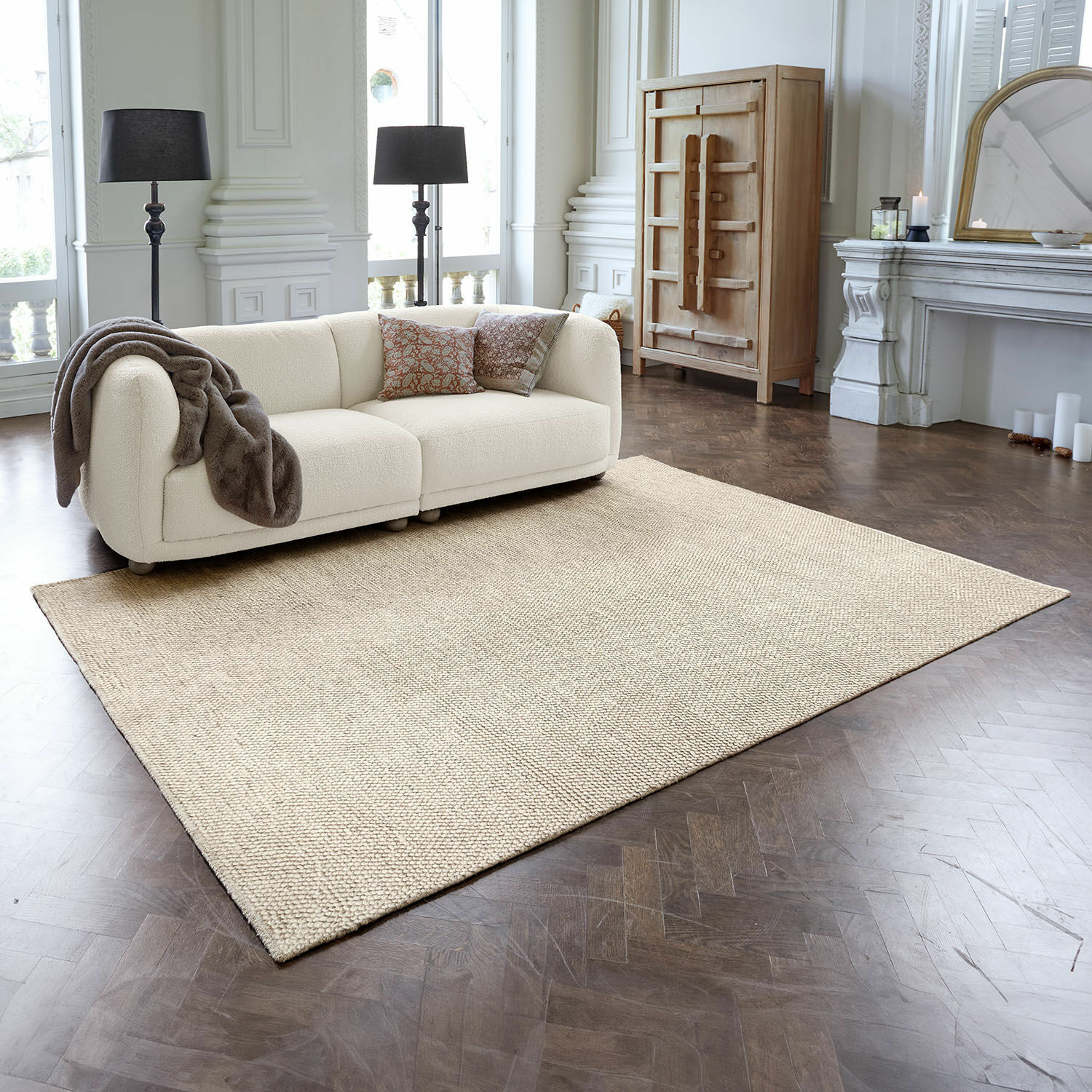 Vloerkleed Coleman Beige vloerkleed van natuurlijk materiaal op donkere houten vloer in elegante woonkamer met bank
