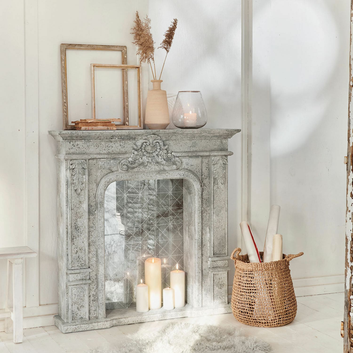 Haardschouw Rethonvillers Decoratieve grijze stenen schouw met brandende kaarsen en rieten mand op witte vloer