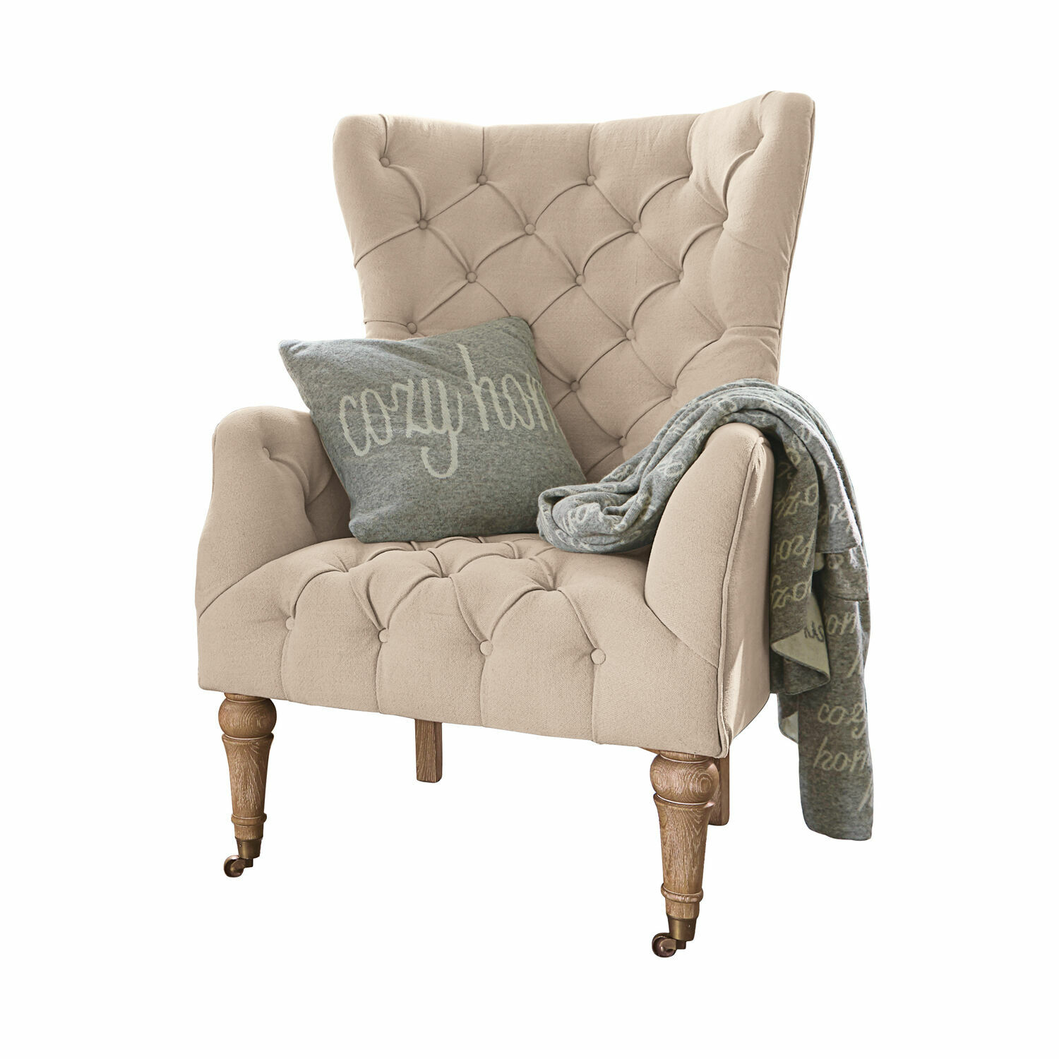 Fauteuil Migré Beige gestoffeerde fauteuil met houten poten, grijs kussen en cozy home deken