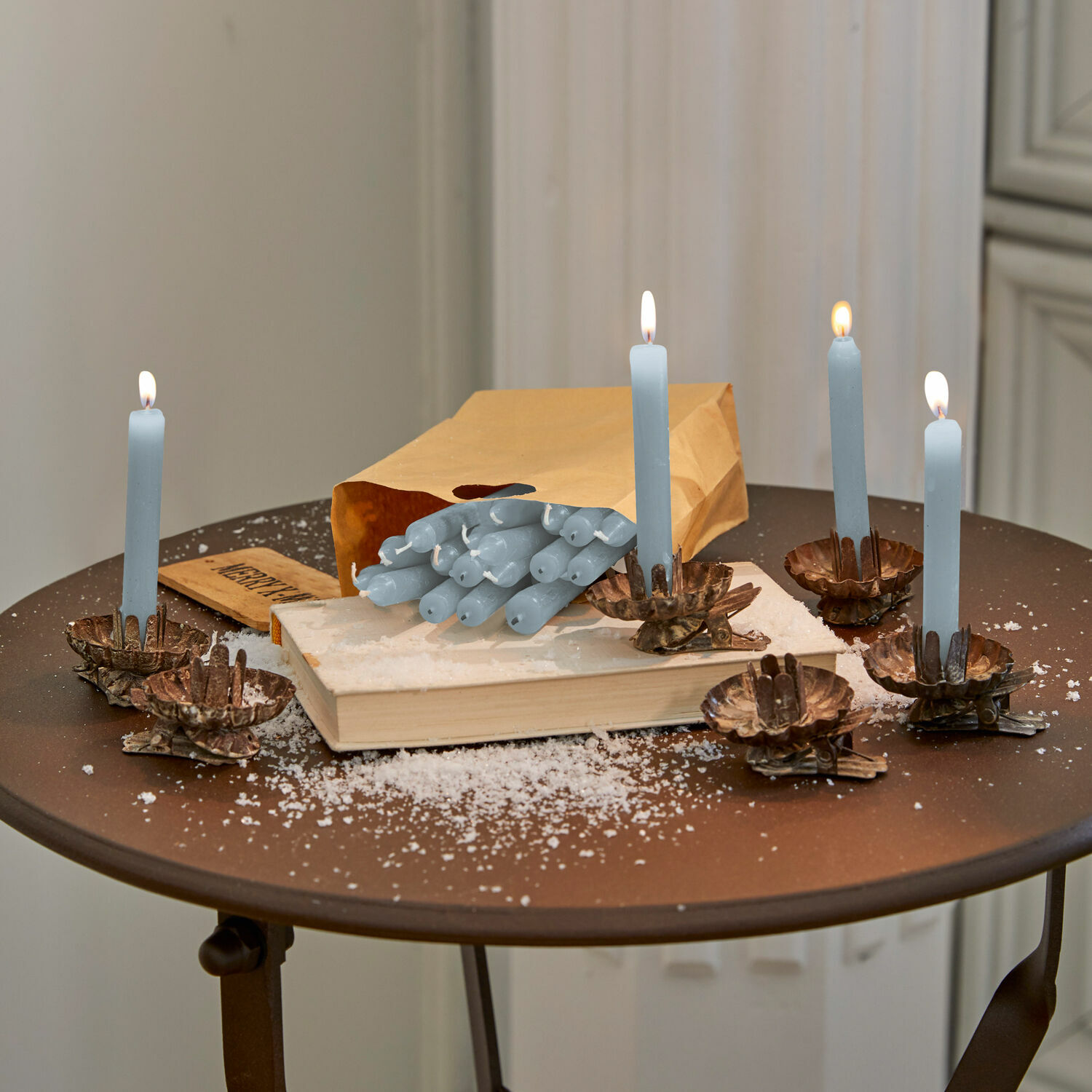 Lot de 20 bougies Noufa Bougies bleues avec chandeliers en métal sur une table marron avec livre et sac en papier