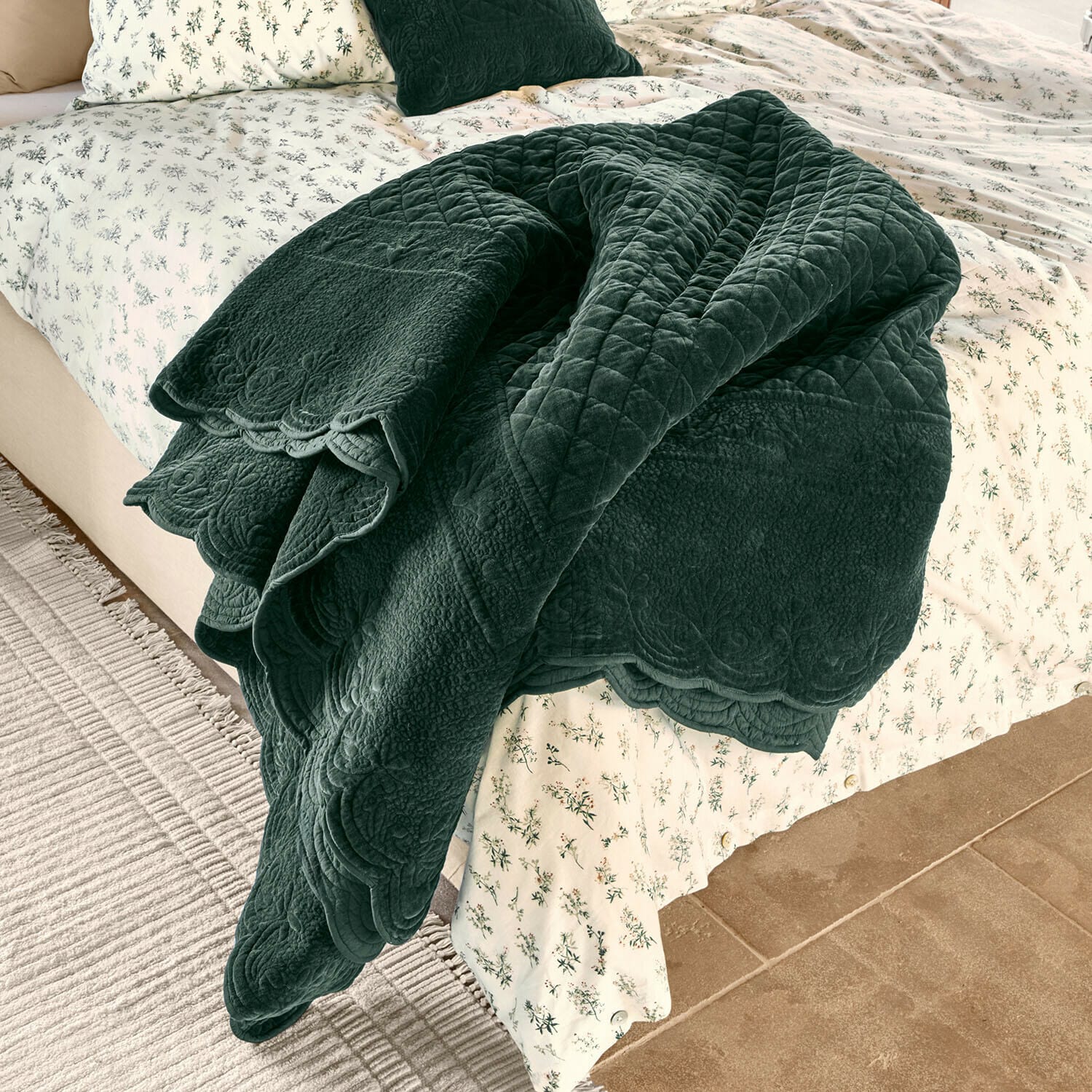 Courtepointe Lunévois Plaid matelassé vert foncé en tissu doux posé sur un lit avec une literie claire à motifs floraux