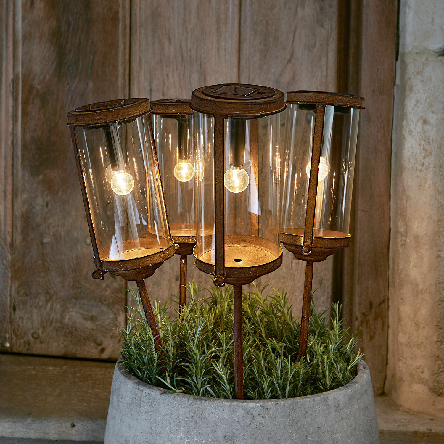 Lantaarn op zonne-energie Set van vier roestige tuinlampen met glazen kap en warm LED-licht in een betonnen pot