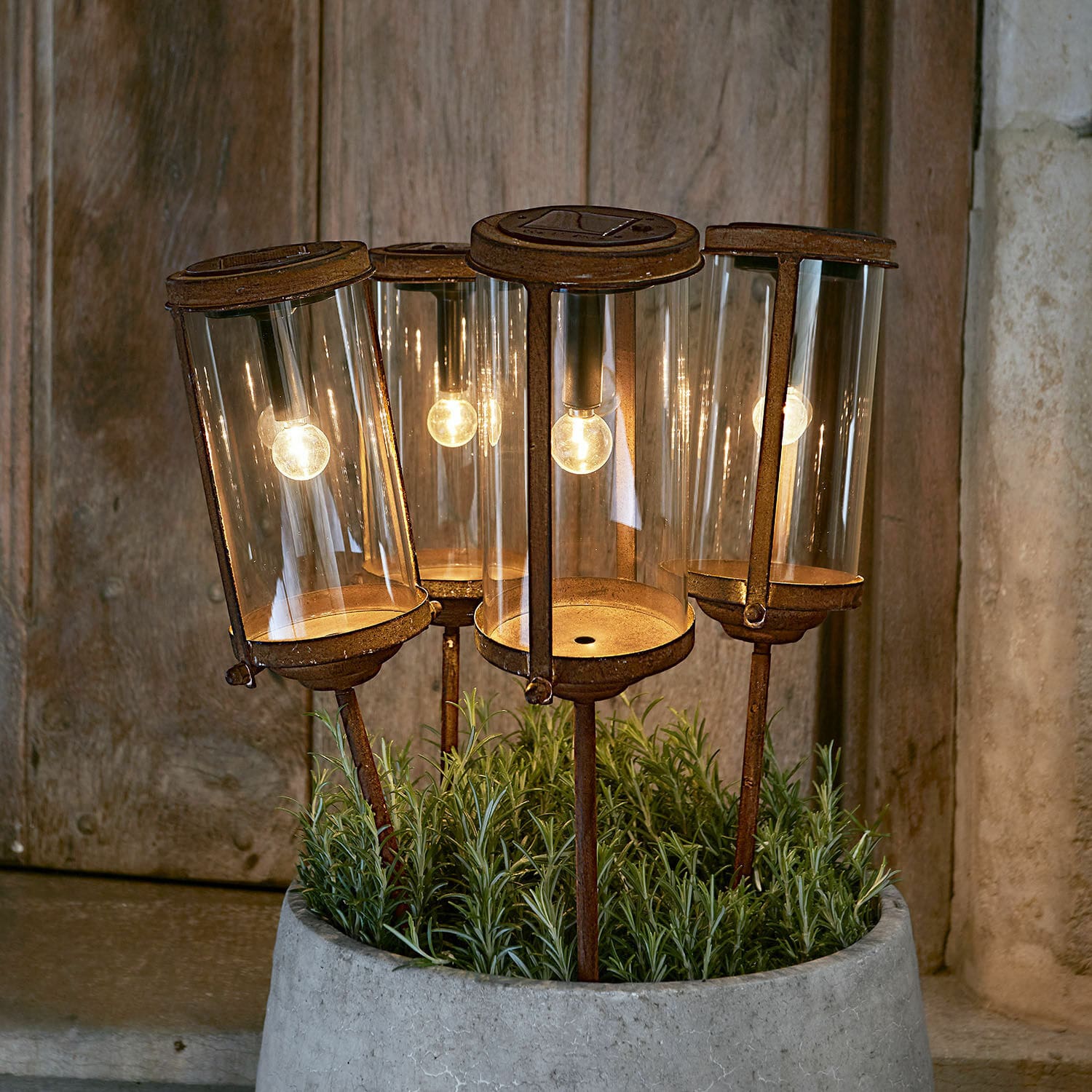 Lanterne solaire Mynesto Ensemble de quatre lanternes de jardin rouillées avec abat-jours en verre et lumière LED chaude dans un pot en béton