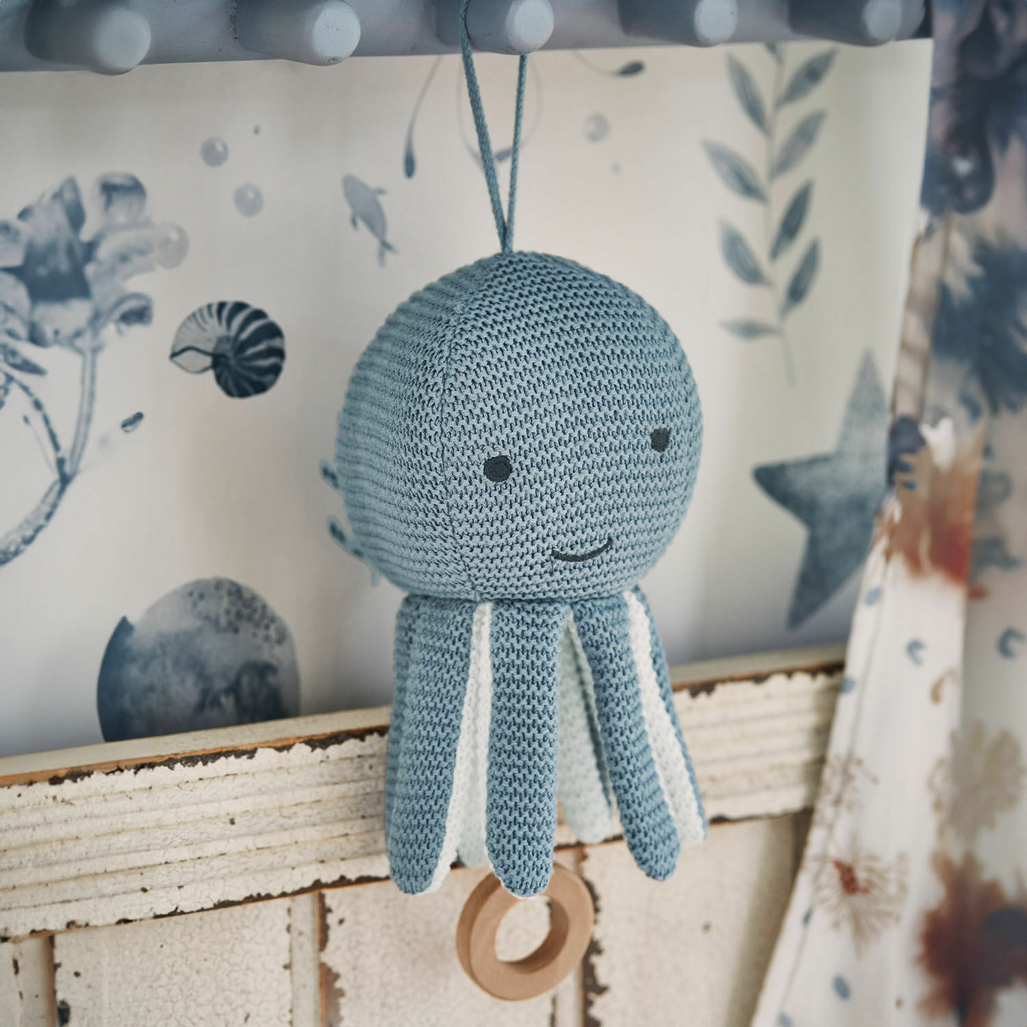 Peluche musicale Cozycot Jouet pieuvre tricoté bleu avec détails blancs et anneau en bois suspendu, décoration enfantine douce