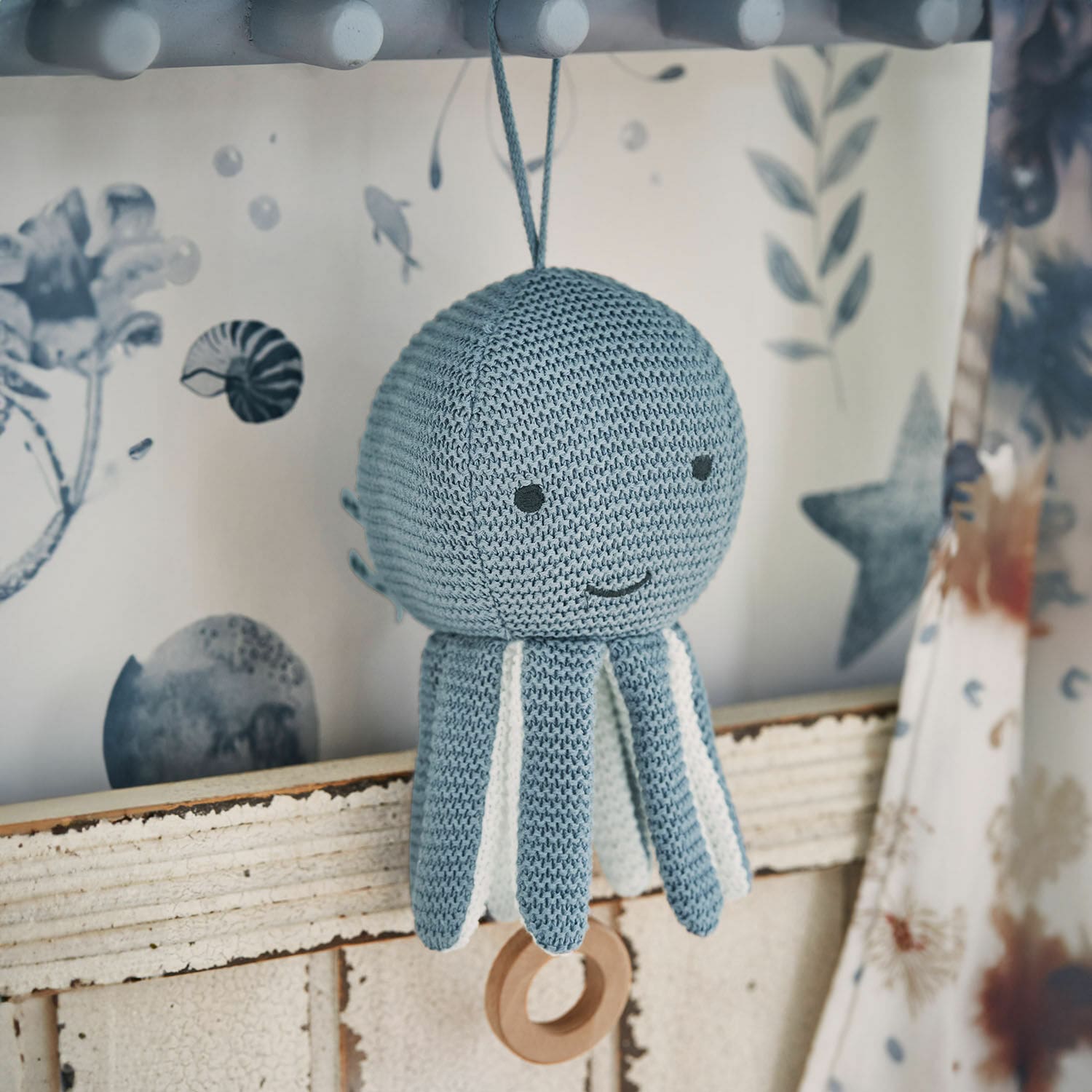 Peluche musicale Cozycot Jouet pieuvre tricoté bleu avec détails blancs et anneau en bois suspendu, décoration enfantine douce