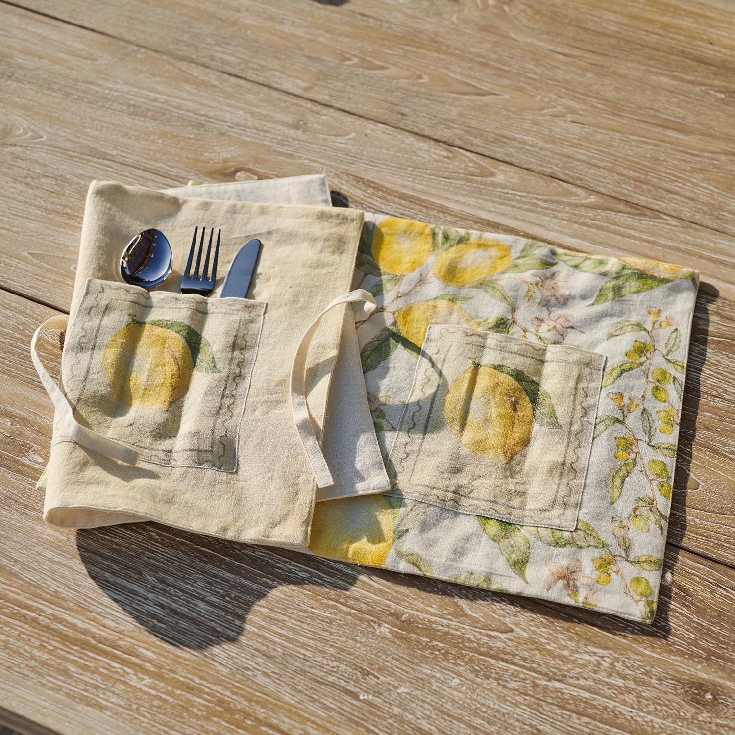 Lot de 2 sets de table Lantagenet Housse en lin pour couverts avec poche et motif citron jaune posée sur une table en bois clair