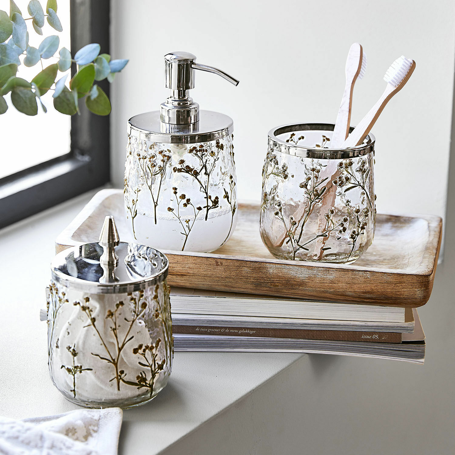 Glazen badkamer set met bloemenpatroon en metalen accenten op houten dienblad