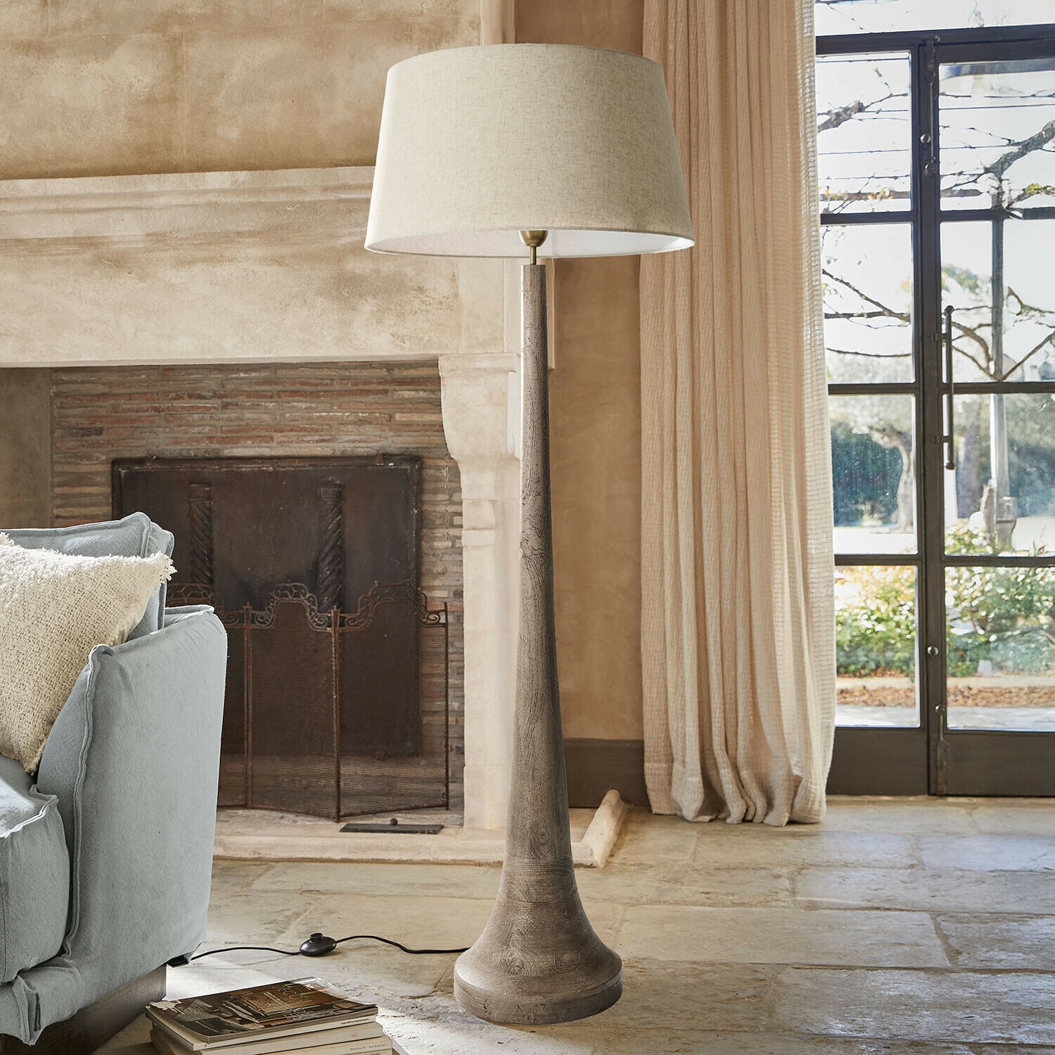 Vloerlamp Helsfjord Staande lamp met houten voet en beige kap in een gezellige woonkamer met open haard en bank