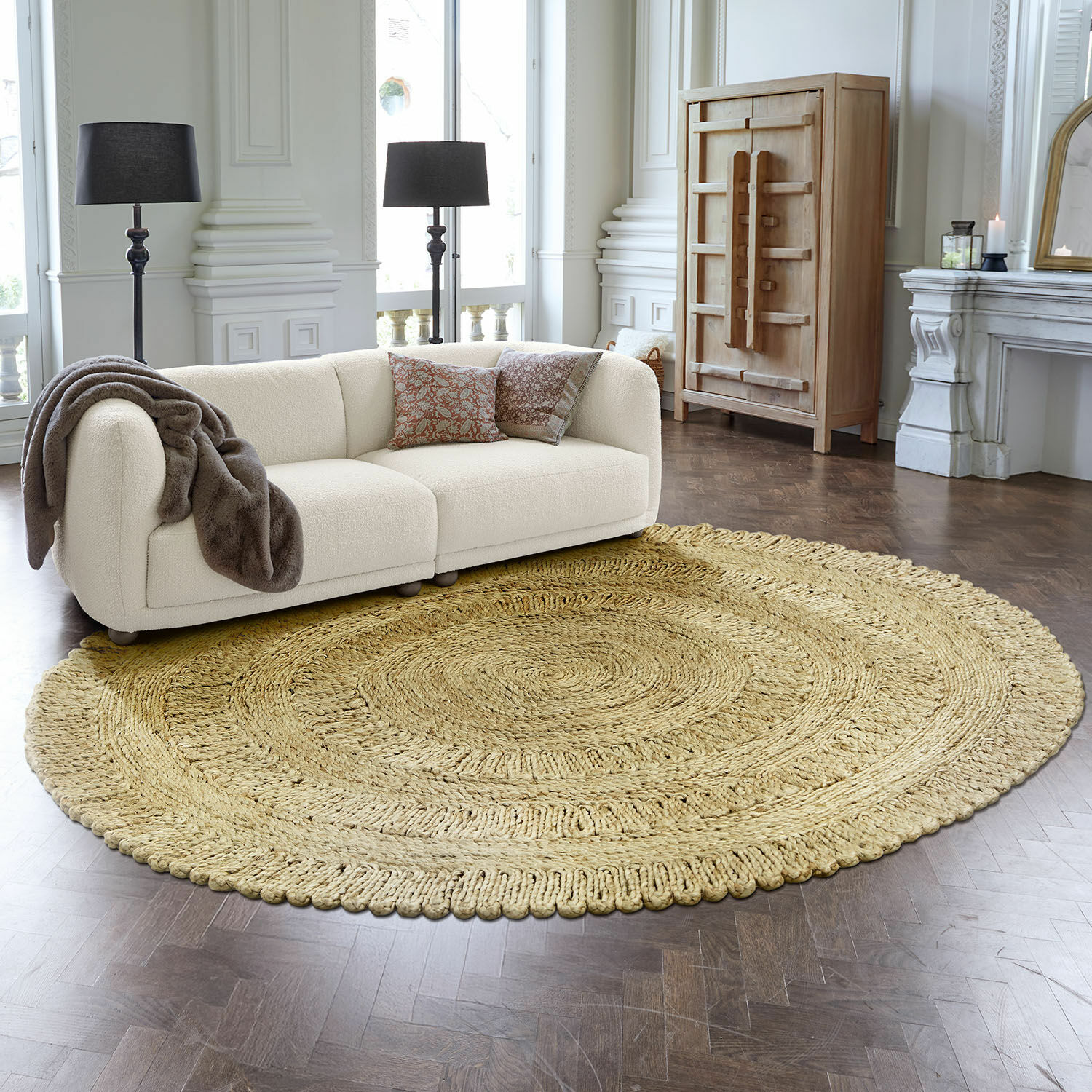 Vloerkleed Arendel Ronde beige vloerkleed van natuurlijk materiaal in moderne woonkamer met witte bank en zwarte lampen
