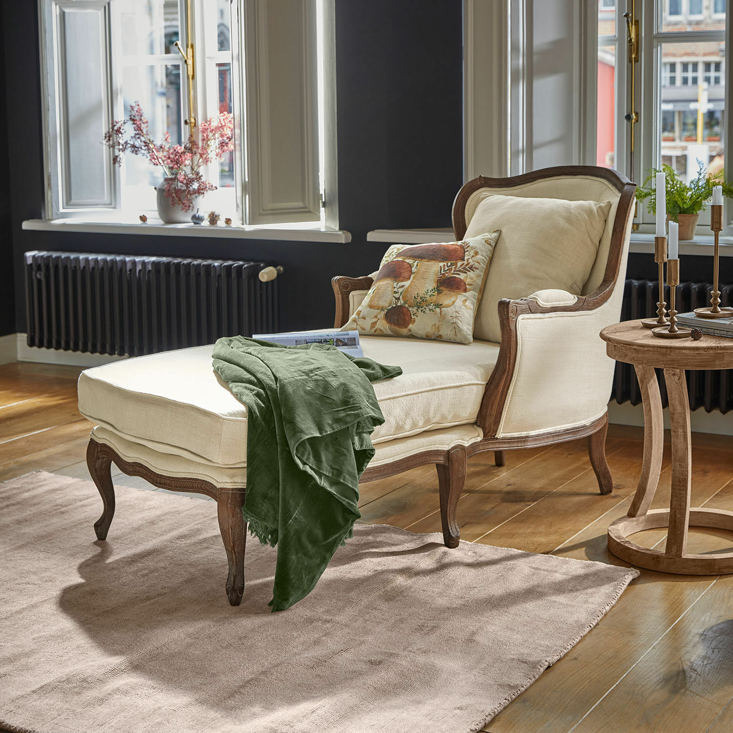 Méridienne Muel Chaise longue beige en bois avec couverture verte dans un salon lumineux au sol en bois