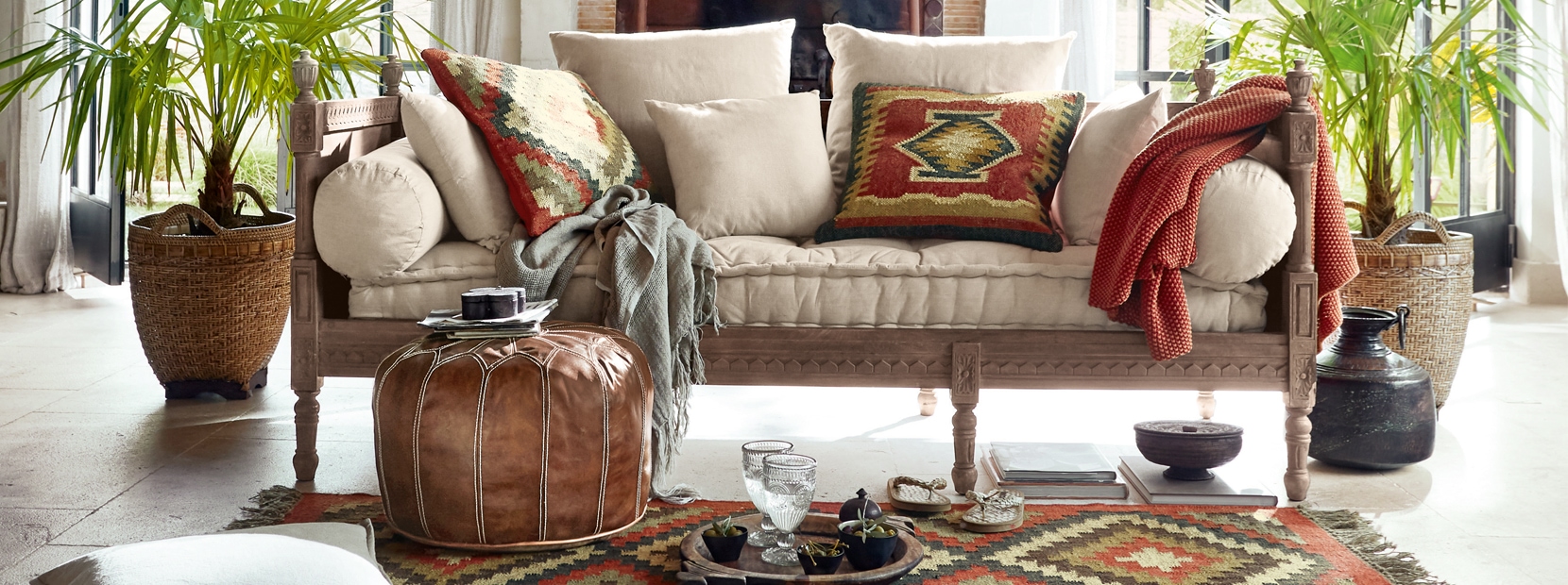 Canapé clair avec coussins et tapis aux motifs orientaux dans un salon lumineux et décoré