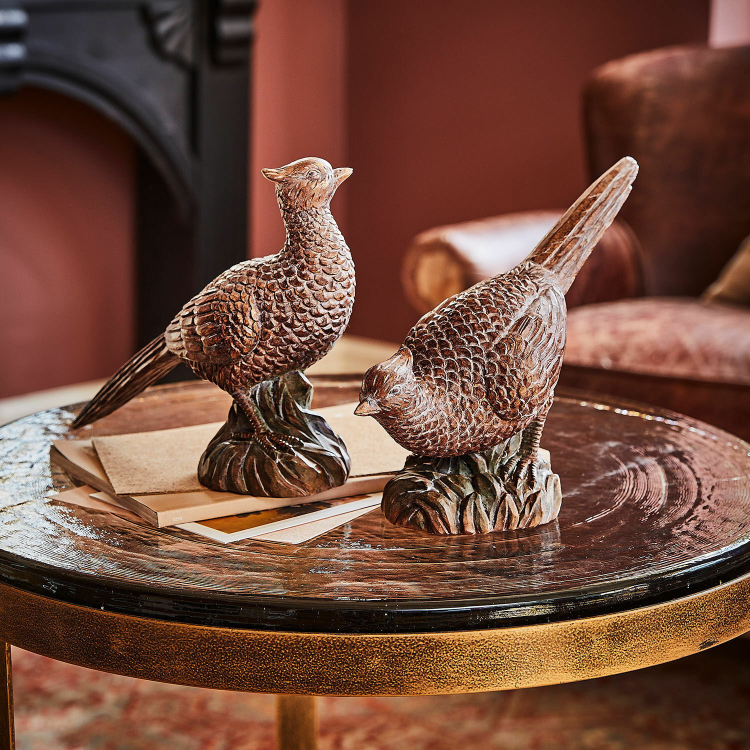 Lot de 2 oiseaux décoratifs Vivoso Deux figurines d'oiseaux en bois brun sur une table en verre dans un salon cosy