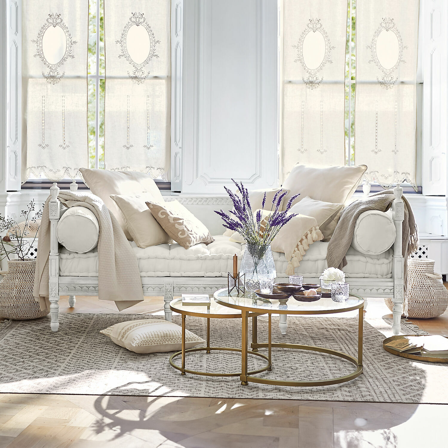 Bank Douville Witte houten bank met crèmekleurige kussens en gouden salontafel in lichte woonkamer