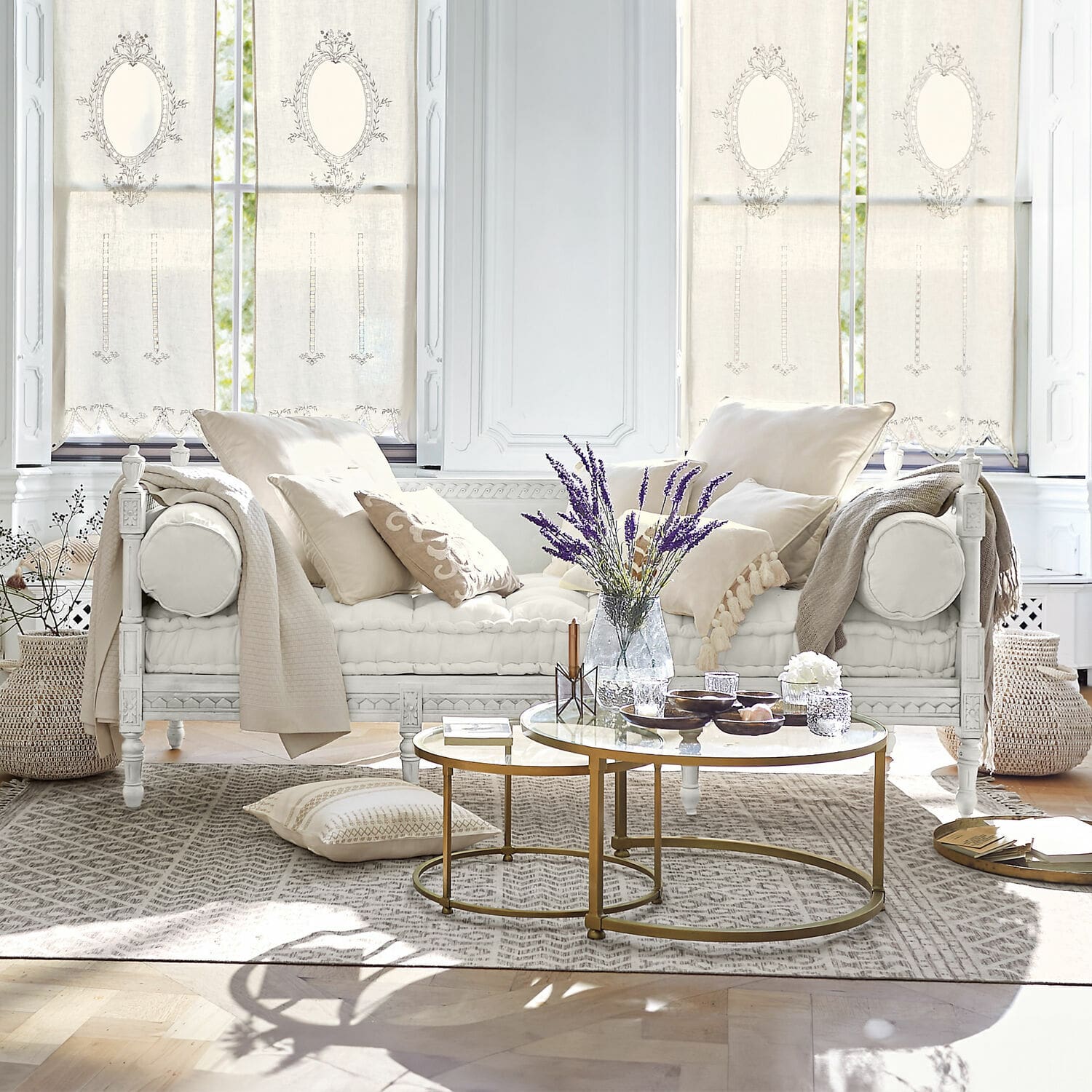 Bank Douville Witte houten bank met crèmekleurige kussens en gouden salontafel in lichte woonkamer