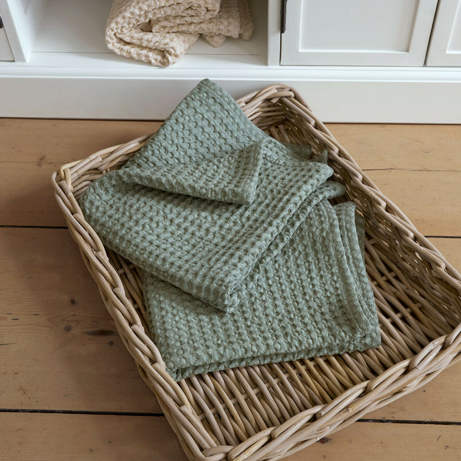 Handdoek set van 2 Maralei Zachte groene katoenen deken met wafelstructuur in een rieten mand op een houten vloer