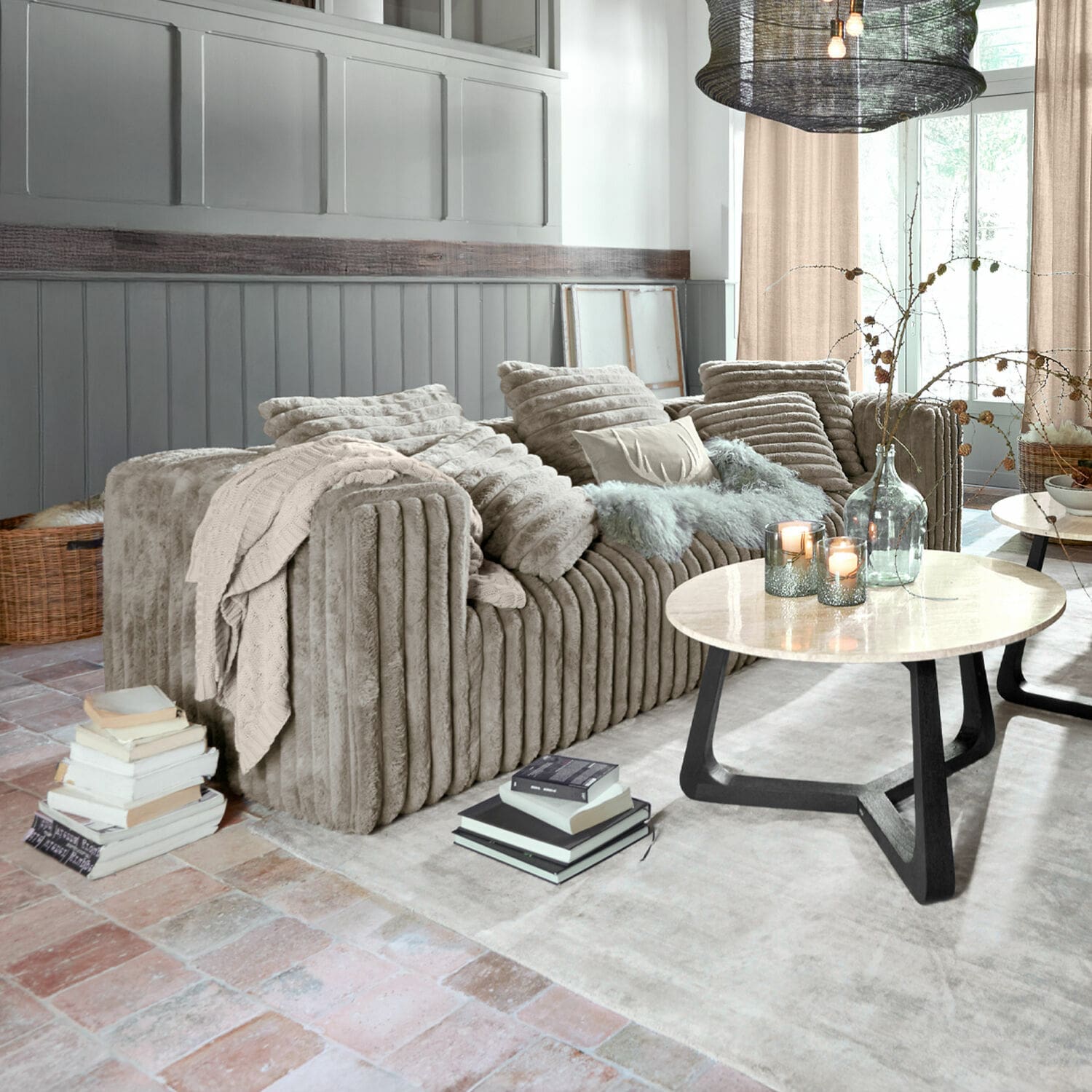 Bank Roucemont Beige pluche bank met kussens en deken in moderne woonkamer met marmeren salontafel