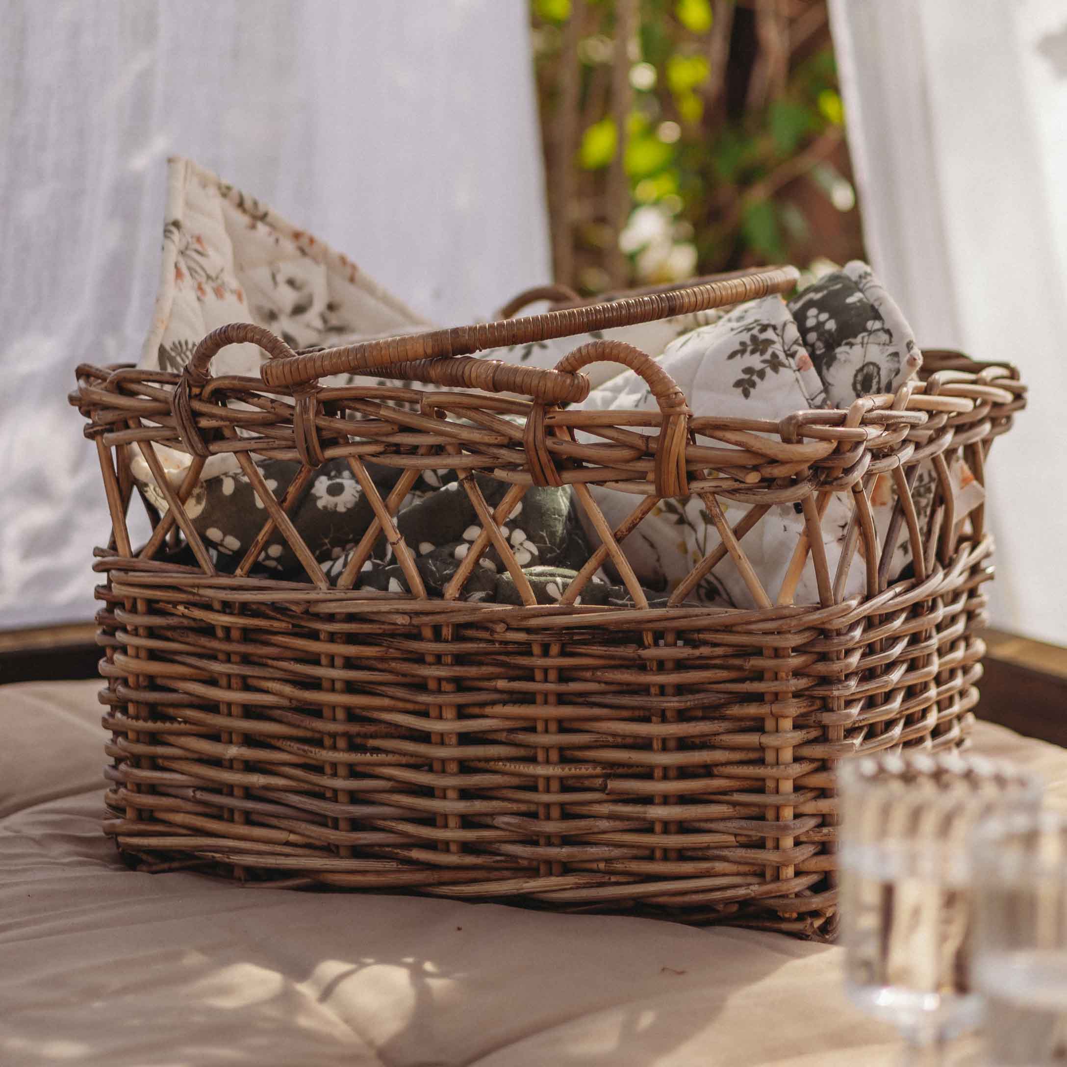 Panier en osier brun naturel avec coussins à motifs floraux, accessoire déco et rangement pratique