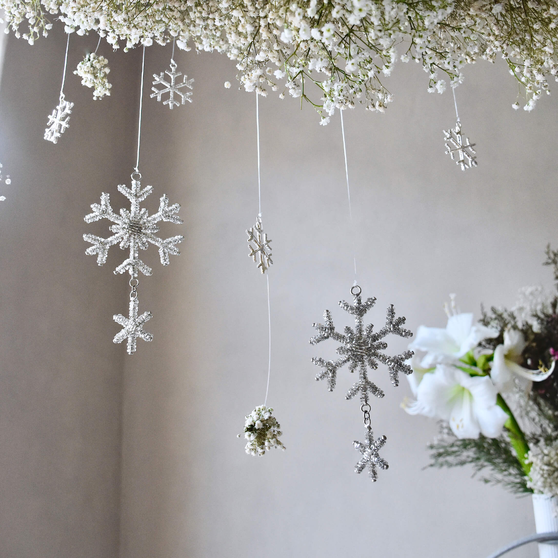 Décorations suspendues flocons de neige blancs et fleurs, ambiance hivernale douce et élégante