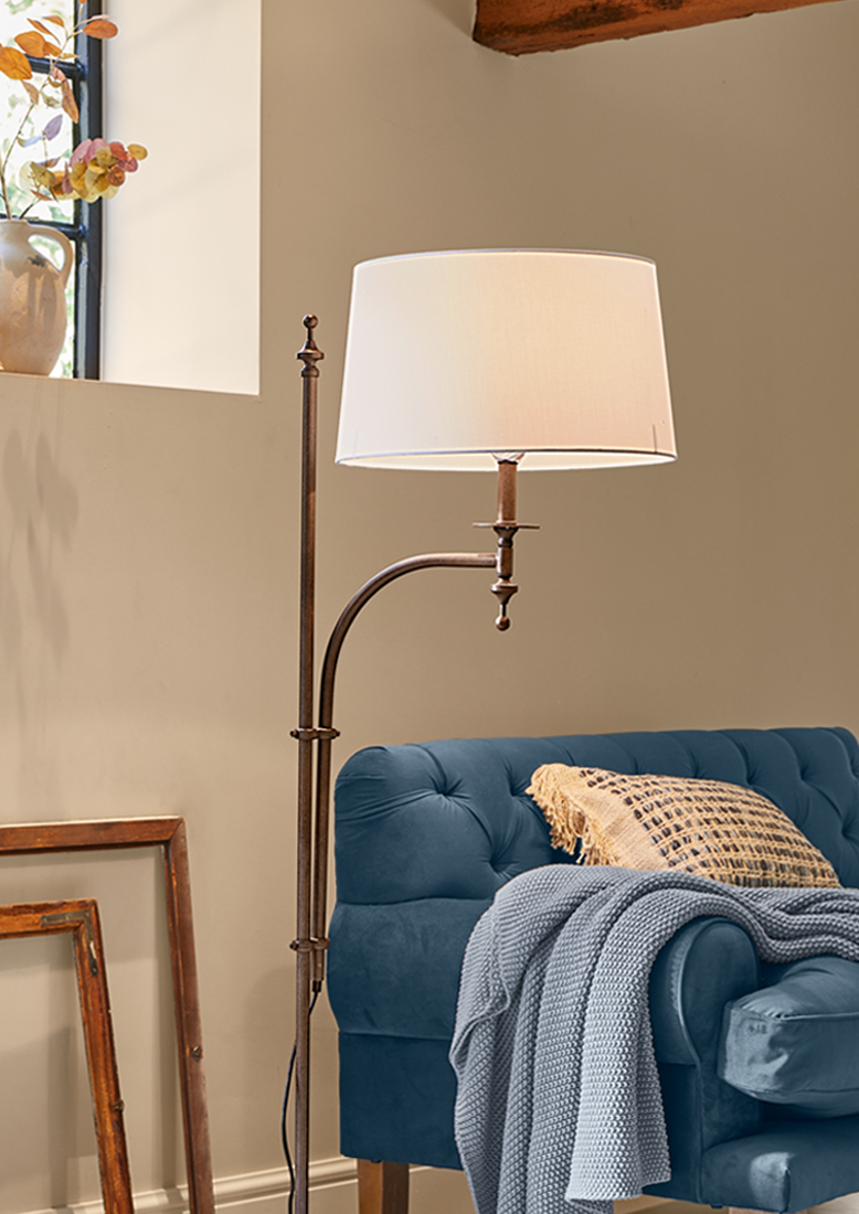 Lampadaire en métal avec abat-jour blanc à côté d'un canapé bleu avec une couverture tricotée