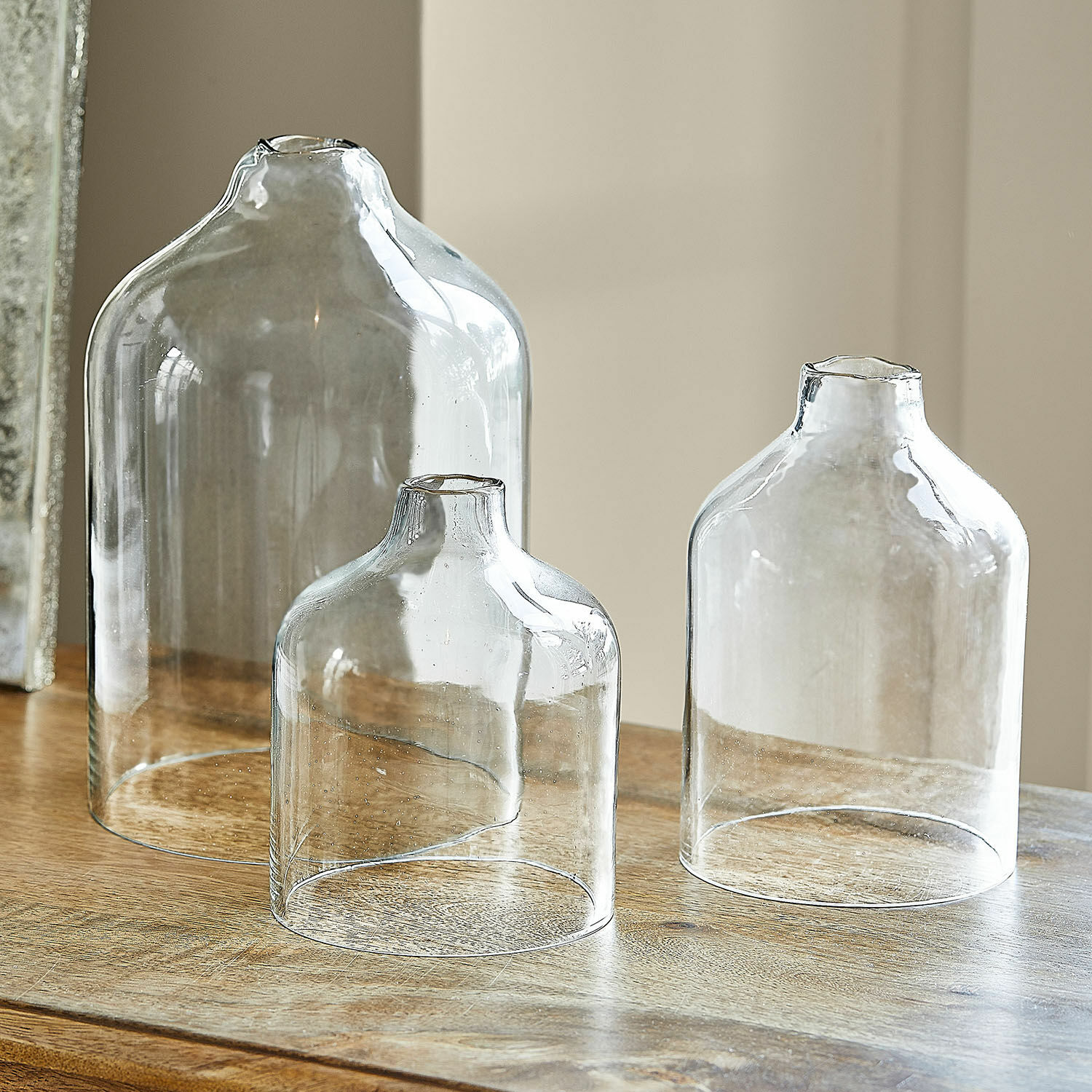 Lot de 3 photophores Xalvent Ensemble de trois vases en verre transparent de tailles différentes sur une table en bois