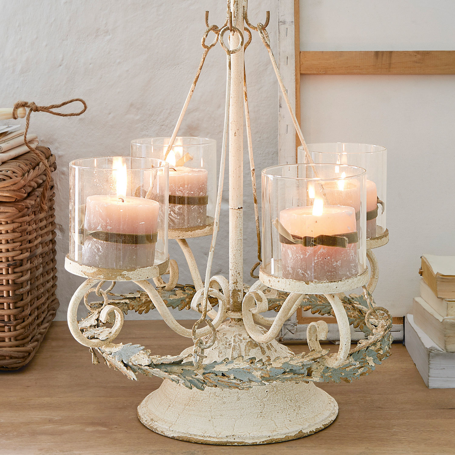 Support pour couronne de l'Avent Denders Chandelier en métal avec quatre bougies roses dans des protections en verre sur une table en bois