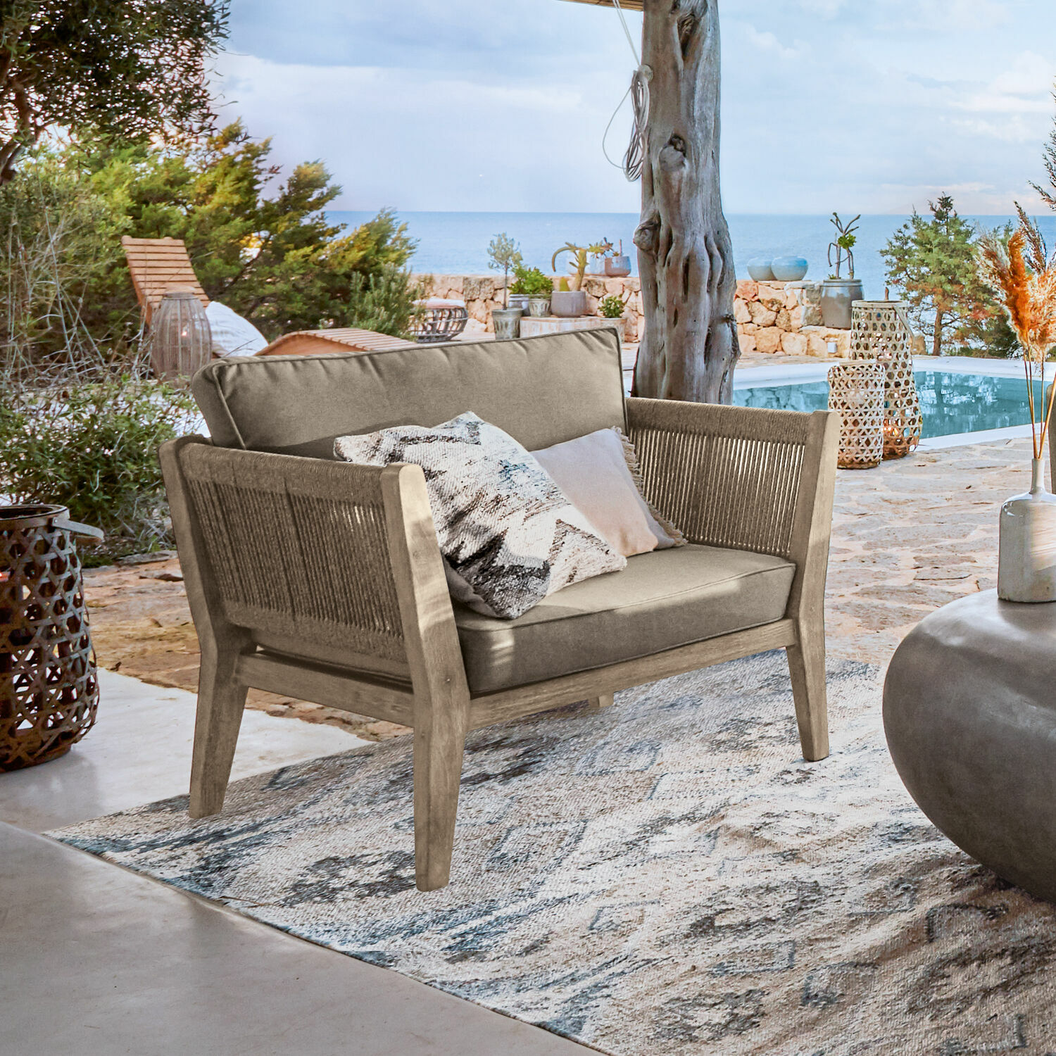 Canapé d'extérieur en bois et tissu beige sur terrasse avec vue sur la mer