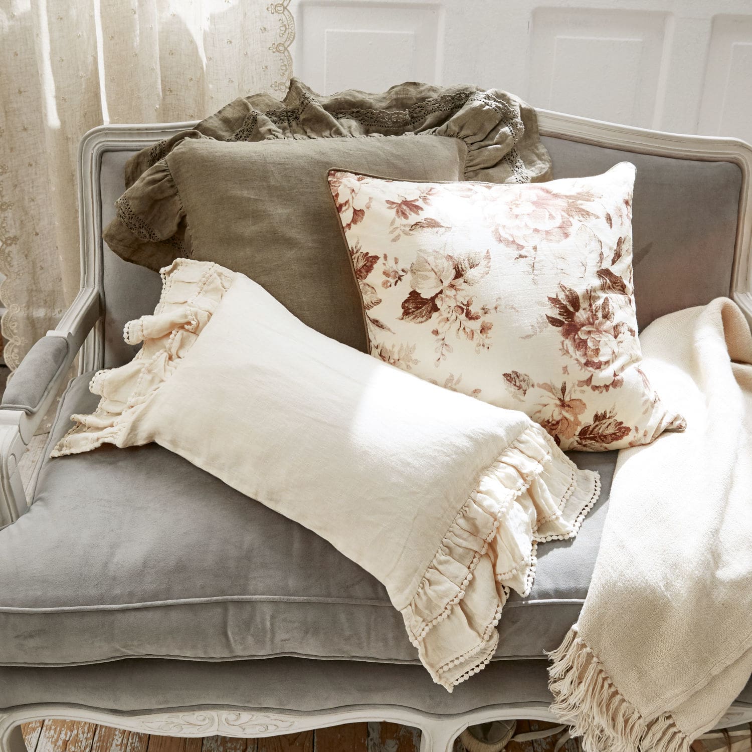 Set decoratieve linnen kussens in beige en bruine tinten op een grijze fluwelen bank