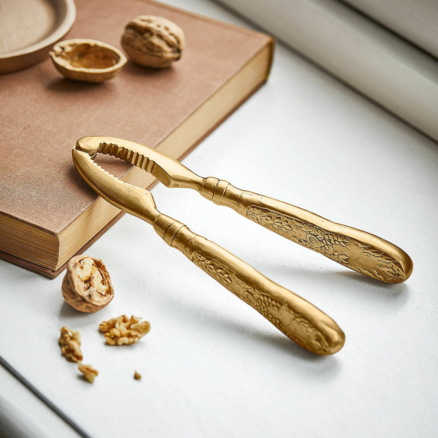 Notenkraker Solenna Gouden metalen notenkraker met decoratief patroon op de handvatten op witte achtergrond