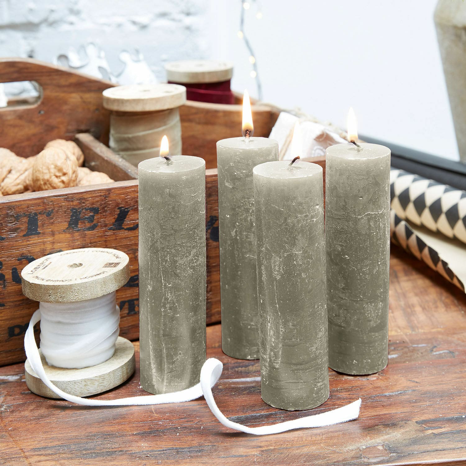 Kaars set van 4 Muriel Vier grijze stompkaarsen op houten tafel met houten spoel en decoraties op de achtergrond
