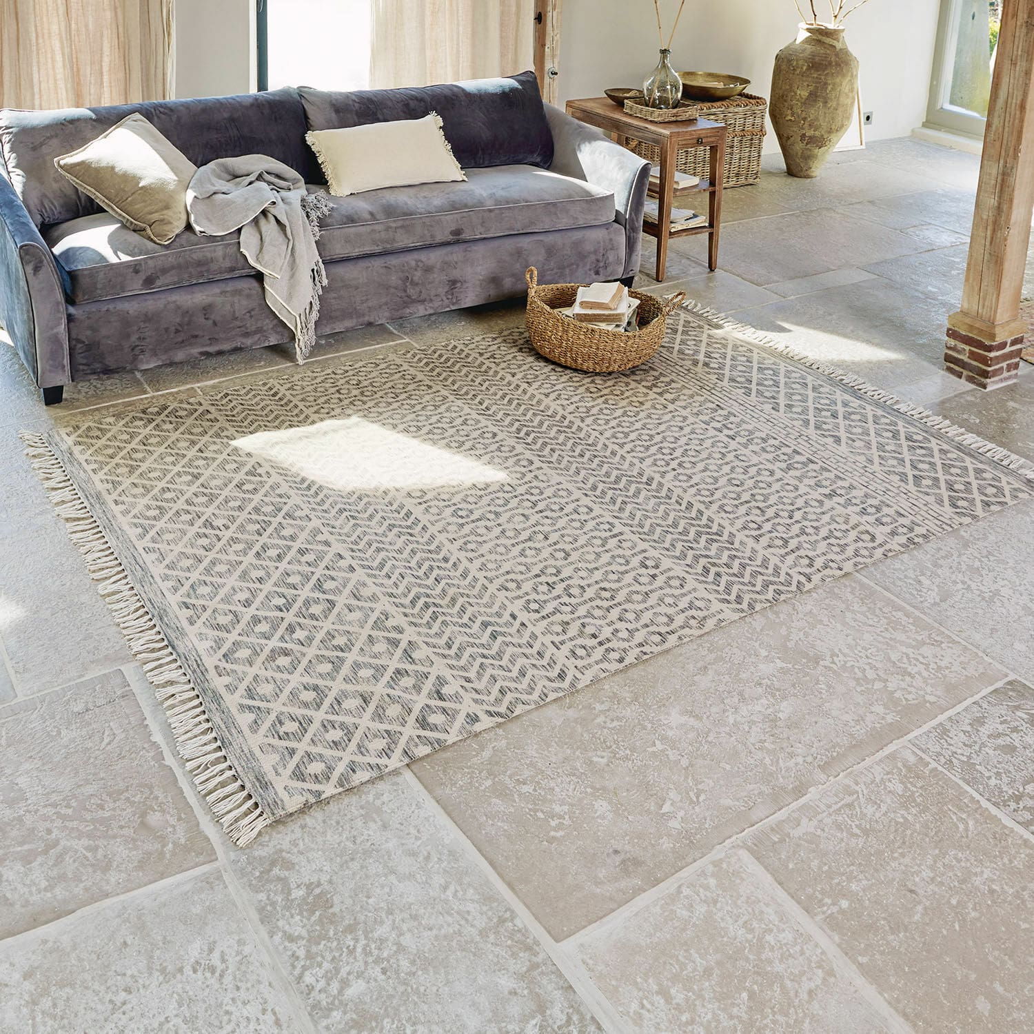 Tapis d'intérieur et d'extérieur Champigny Tapis beige à motifs géométriques avec franges sur sol en pierre dans un salon lumineux