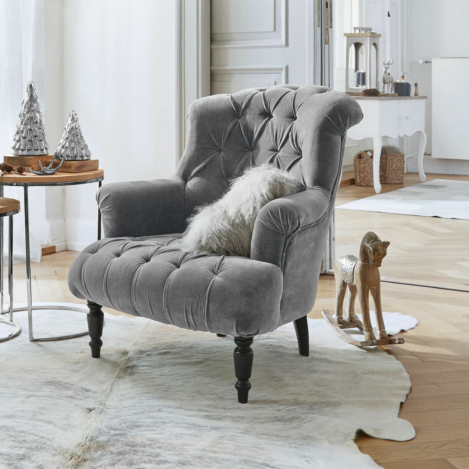 Fauteuil Parranquet Grijze fluwelen fauteuil met knoopstiksels en zwarte houten poten in lichte woonkamer met decoratie