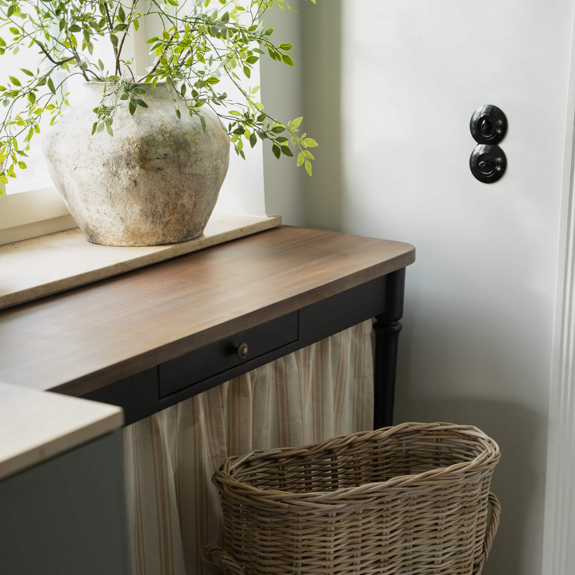 Rustieke lichte stenen vaas met groene takken op een donker houten tafelblad