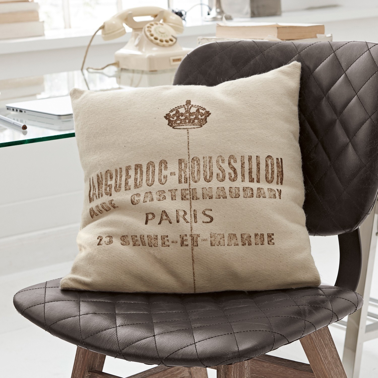 Beige sierkussen met Languedoc-Roussillon print op zwarte doorgestikte leren stoel