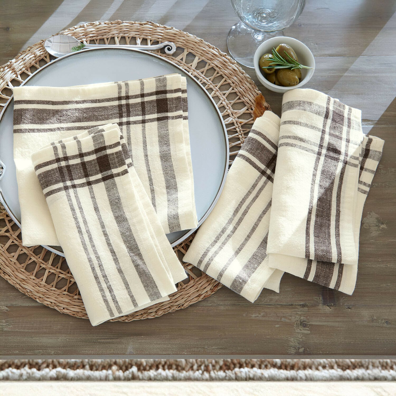Lot de 4 serviettes Ellory Serviettes en lin crème à motif à carreaux marron posées sur une table rustique en bois