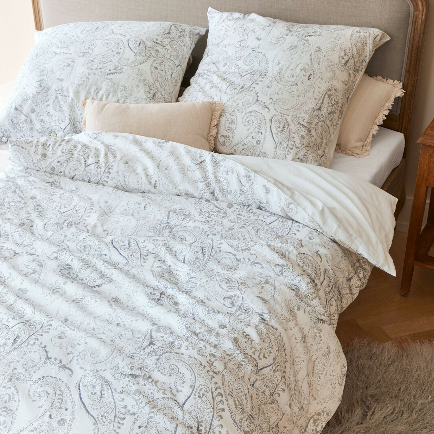 Parure de lit Caselia Parure de lit en coton avec motifs paisley clairs sur lit avec coussins décoratifs beige