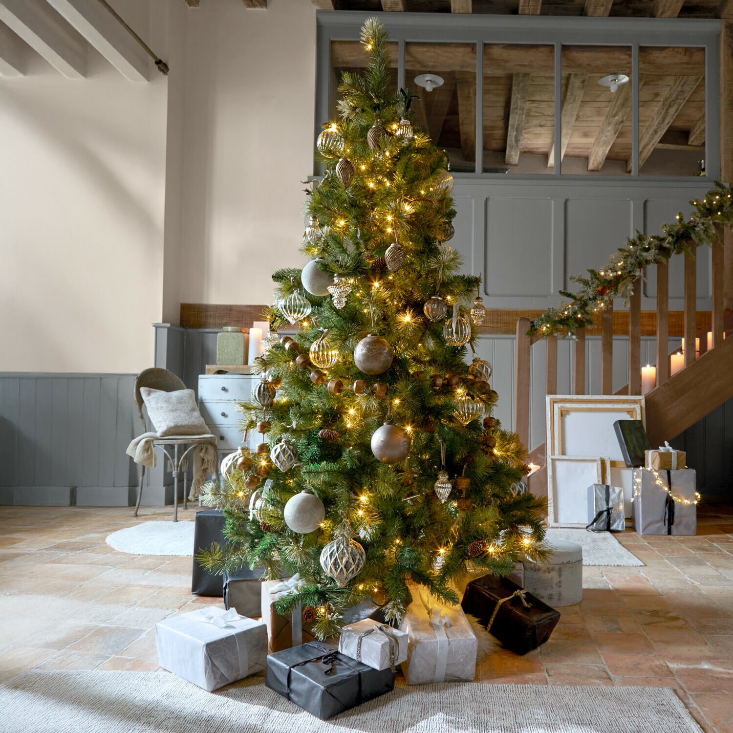 Kerstboom Aure Versierde kerstboom met groene takken en gouden lichtjes in een gezellige kamer met cadeaus