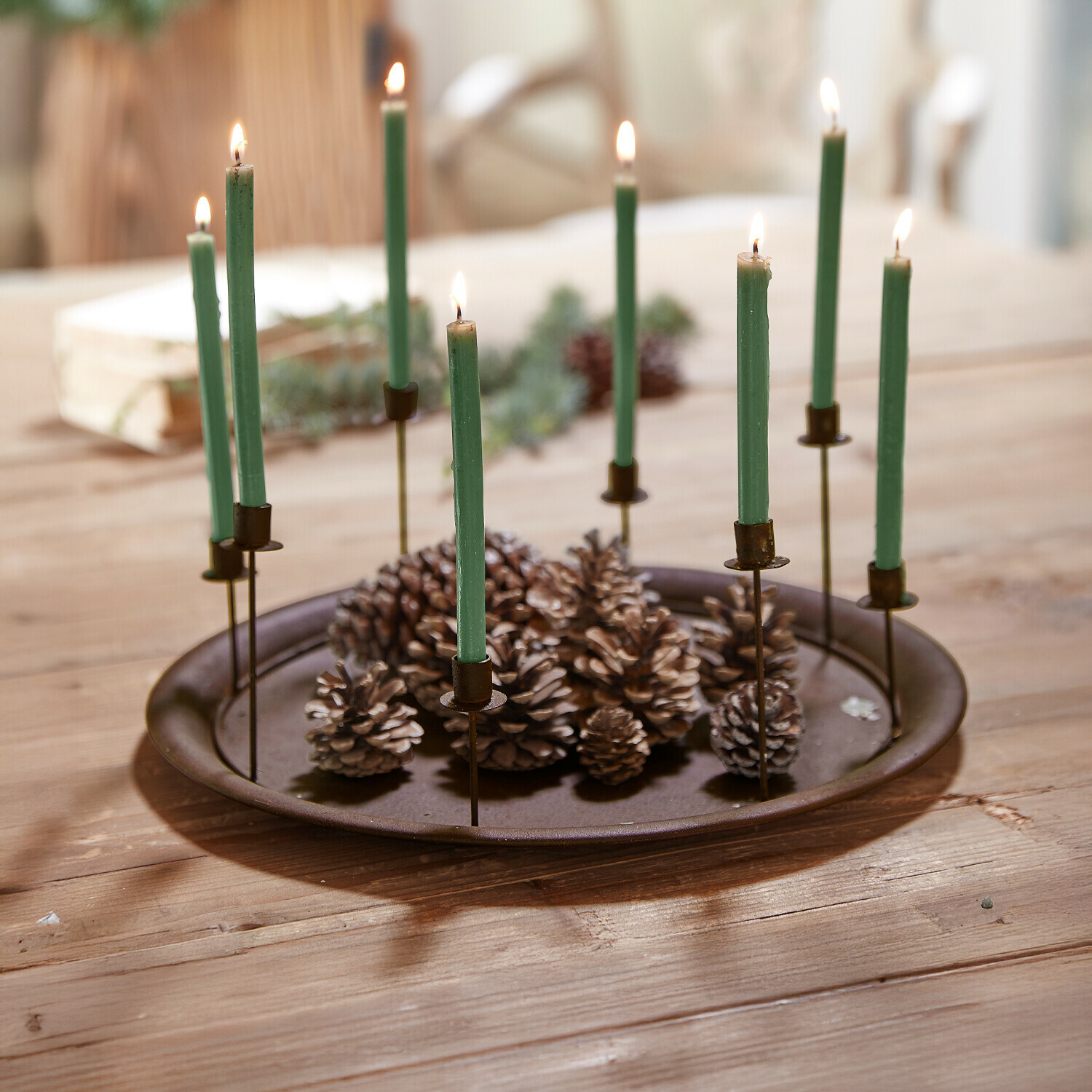 Kaarsenplateau Ophéline Metalen schaal met groene kaarsen en dennenappels op houten tafel, feestelijke decoratie