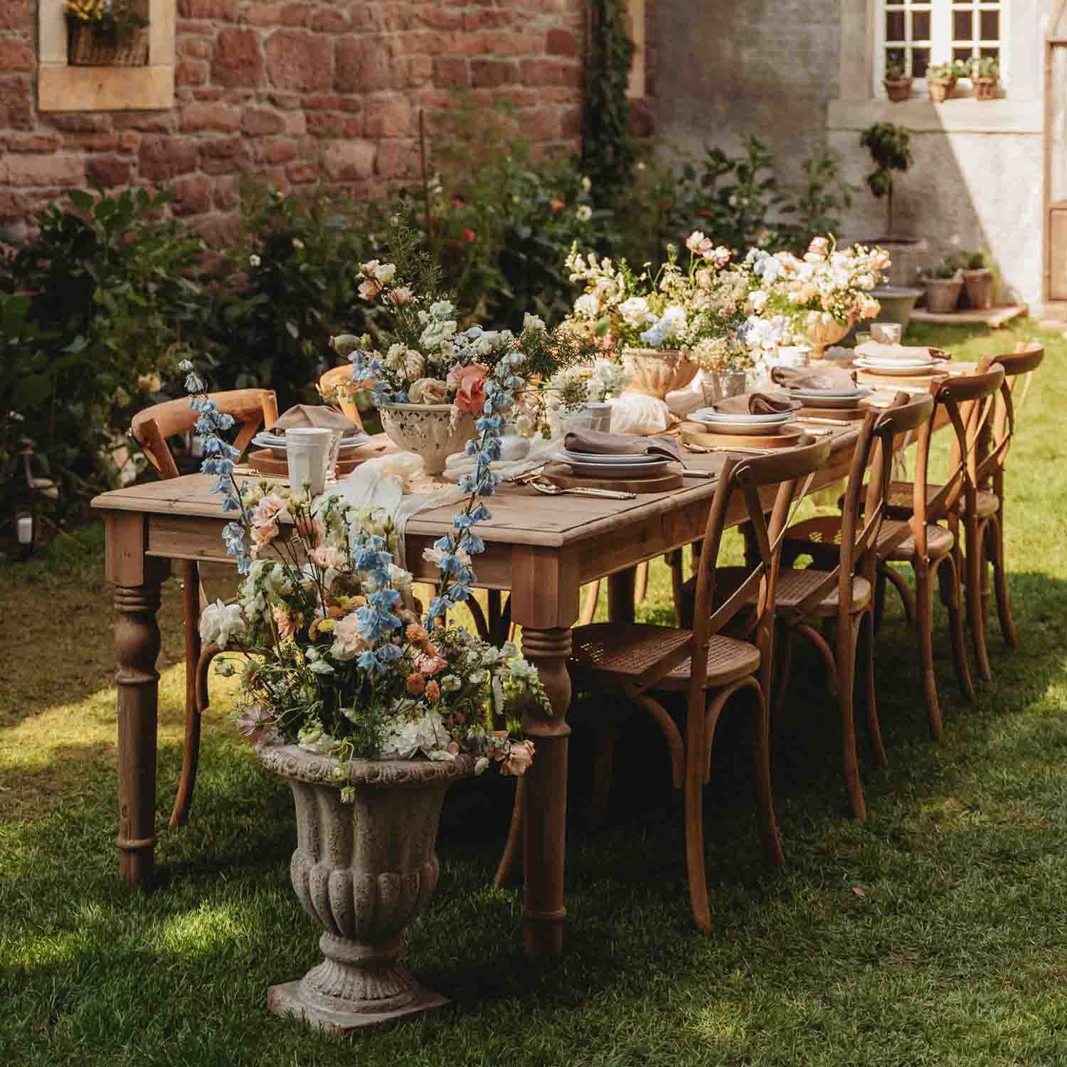Houten tuintafel met bloemendecoratie en servies voor een buitenfeest in de tuin