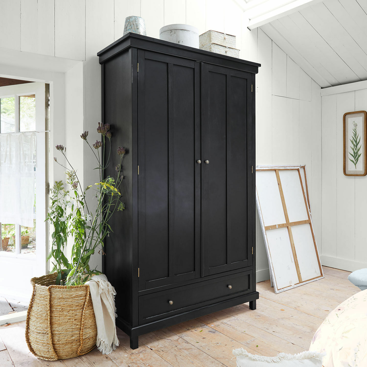 Armoire Sirevol Armoire noire en bois avec deux portes et un tiroir dans une pièce lumineuse et accueillante