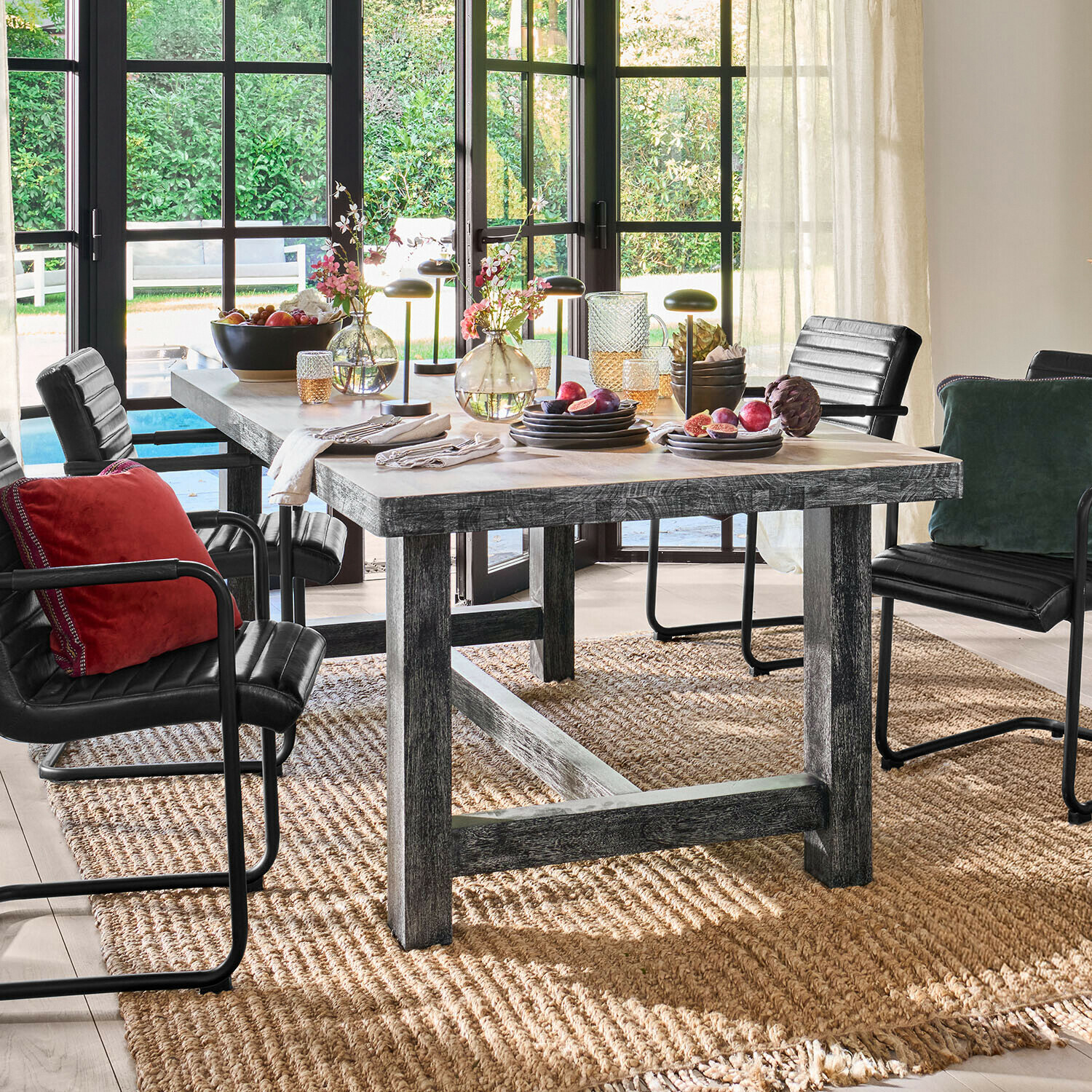 Table à manger en bois rustique avec chaises noires et décorations sur tapis naturel dans une pièce lumineuse