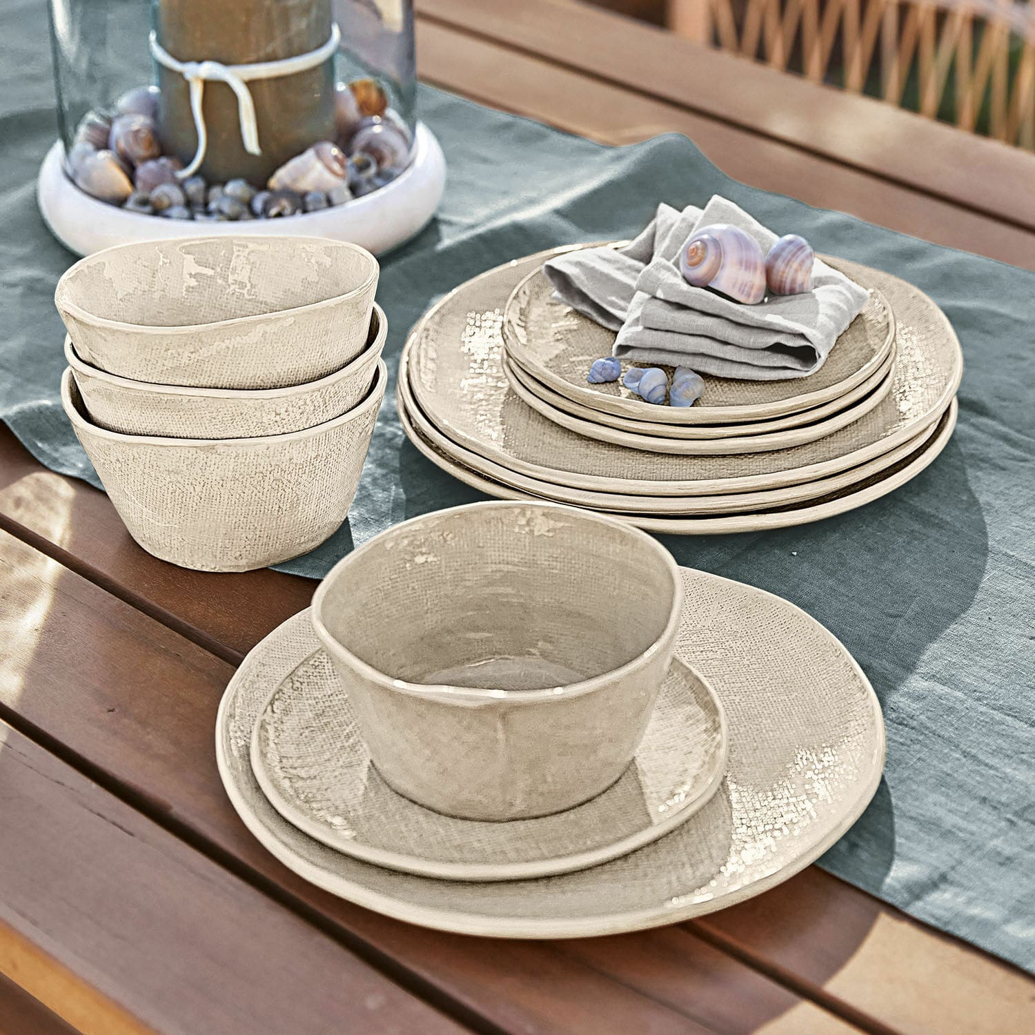 Servies set van 12 Luganville Beige keramisch servies op houten tafel met schelpen en linnen tafelkleed