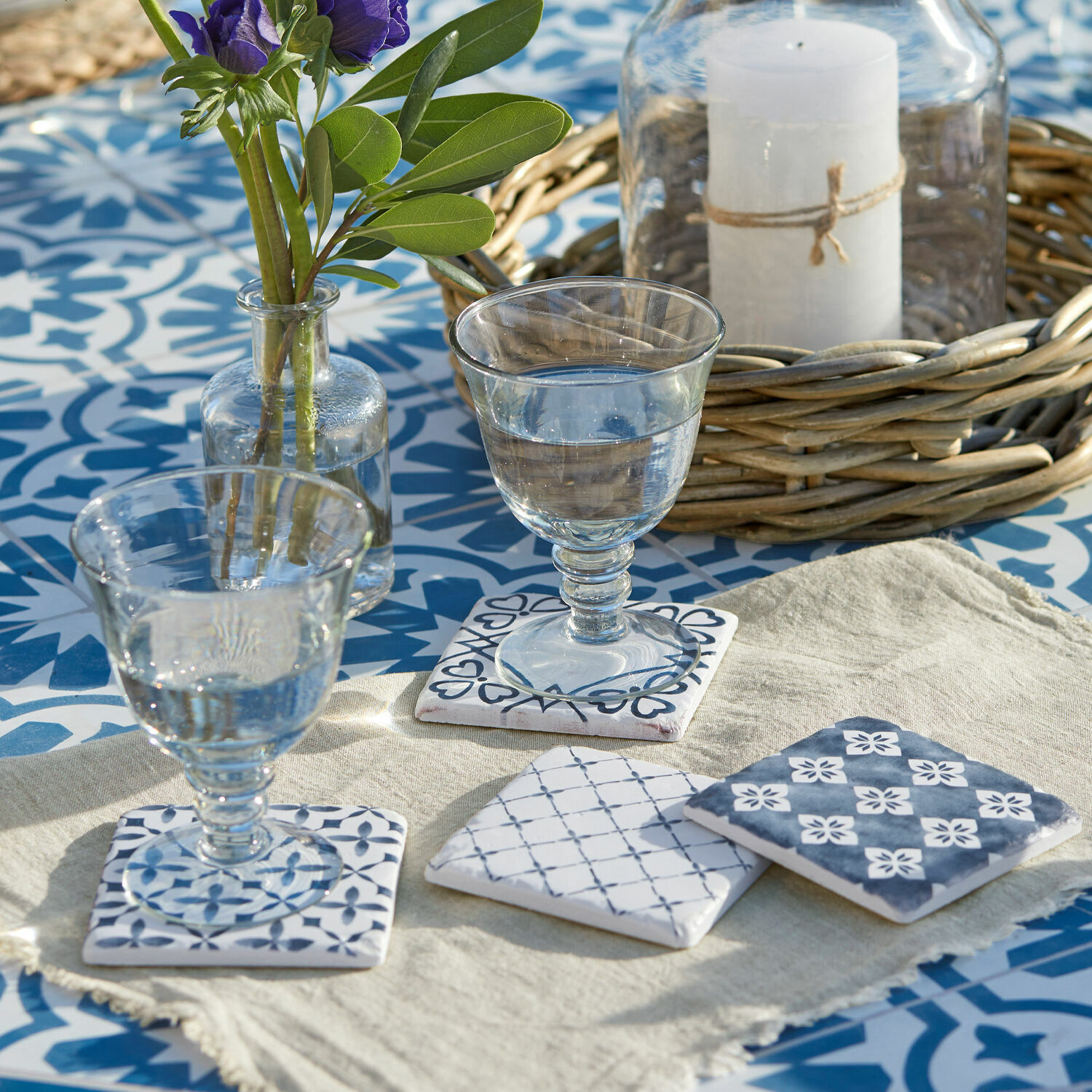 Lot de 4 dessous de verres Sliwa Sous-verres en céramique à motifs bleus sur fond clair posés sur une table à carreaux bleus