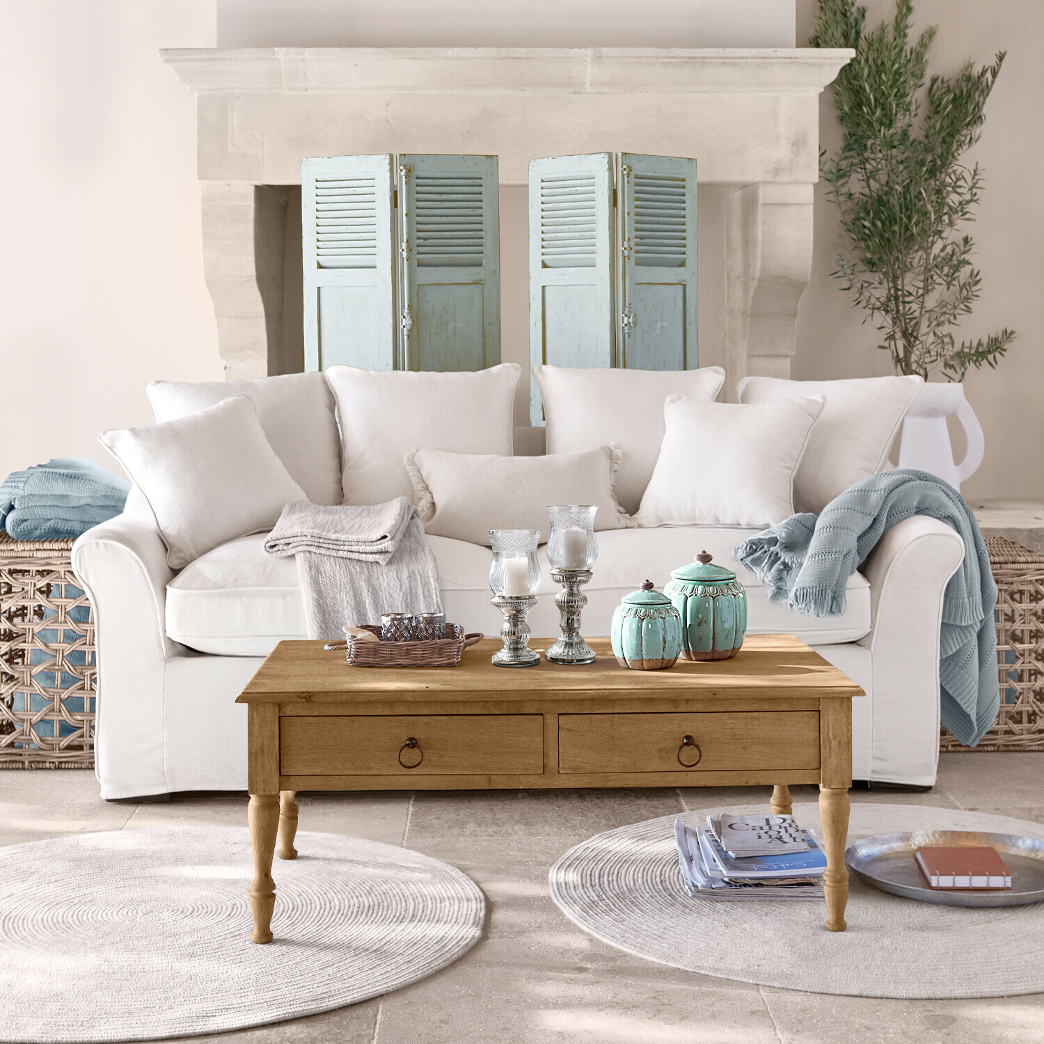 Canapé beige avec coussins et table basse en bois avec décorations dans un salon lumineux avec cheminée