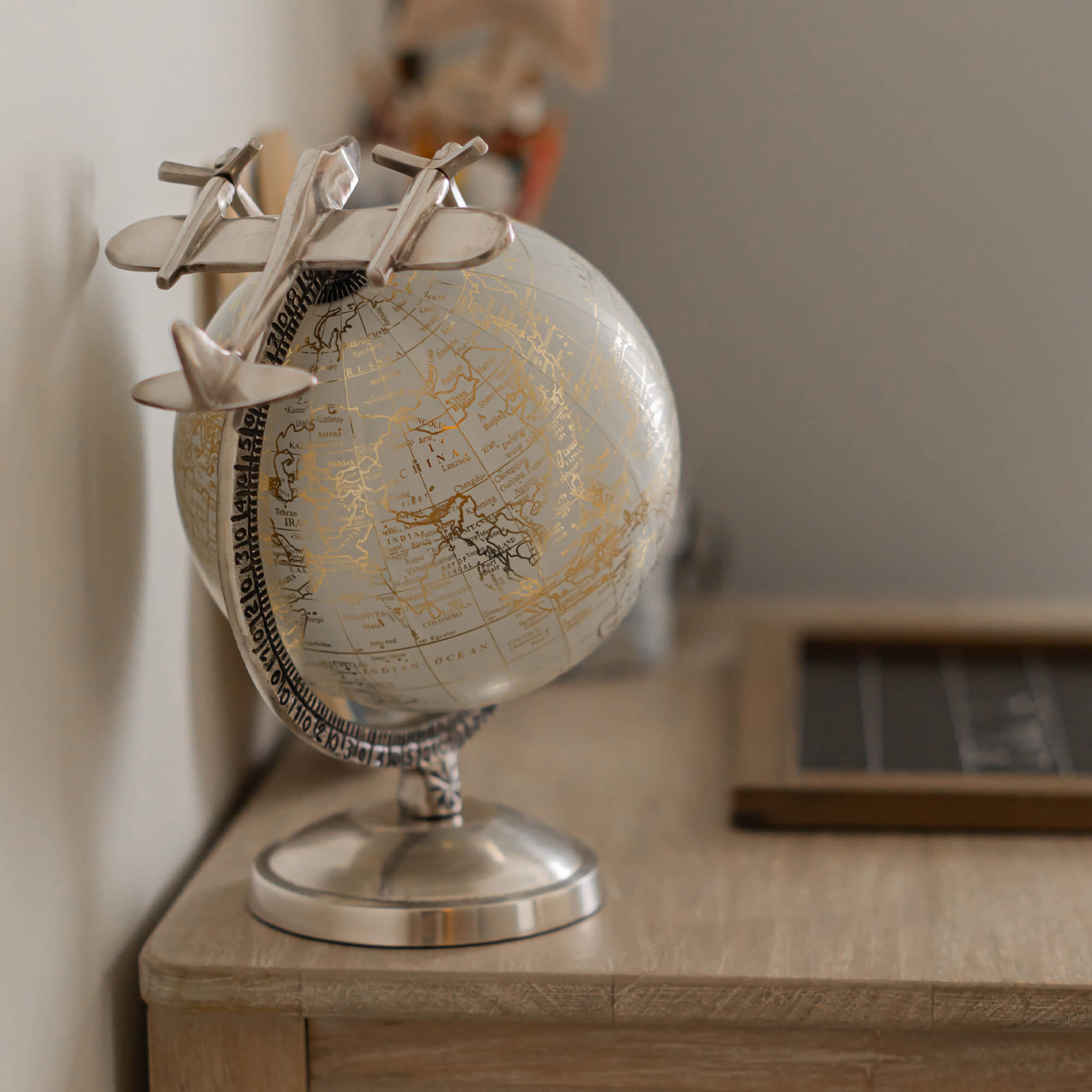 Globe décoratif argenté avec avion en métal posé sur un bureau en bois, accessoire de décoration