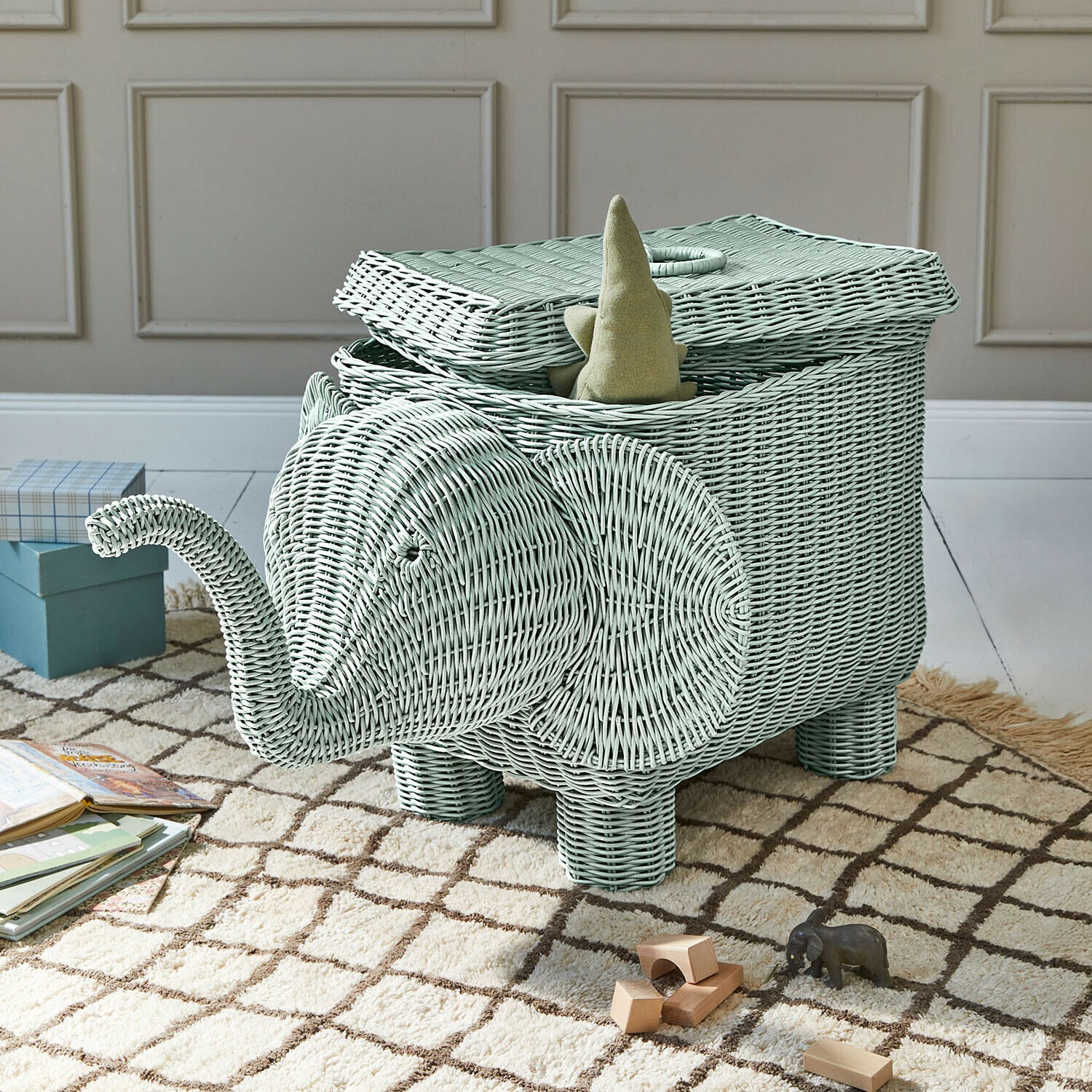 Panier « Éléphant » Bellyboo Panier en rotin vert menthe en forme d'éléphant avec couvercle ouvert et jouets sur tapis