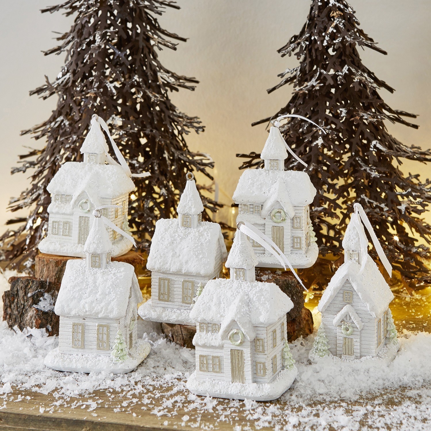 Witte sneeuwhuisdecoraties op houten tafel met metalen kerstbomen en feestelijke verlichting