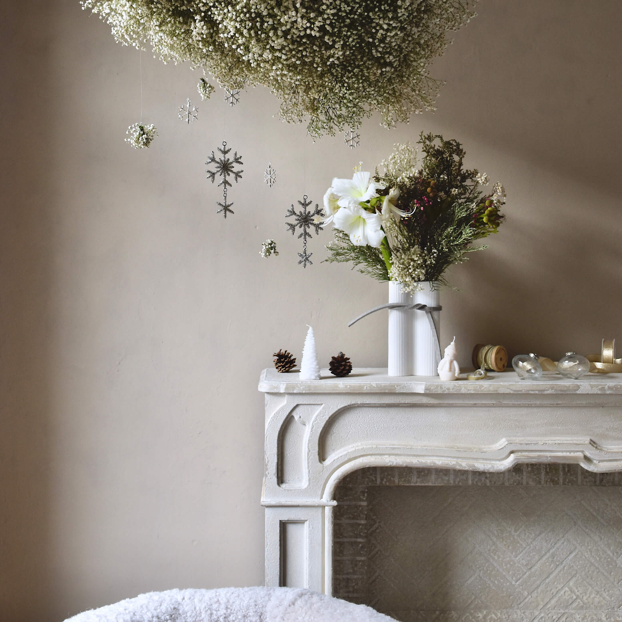 Cheminée blanche décorative avec vase fleuri, décorations de Noël avec pommes de pin et bougies