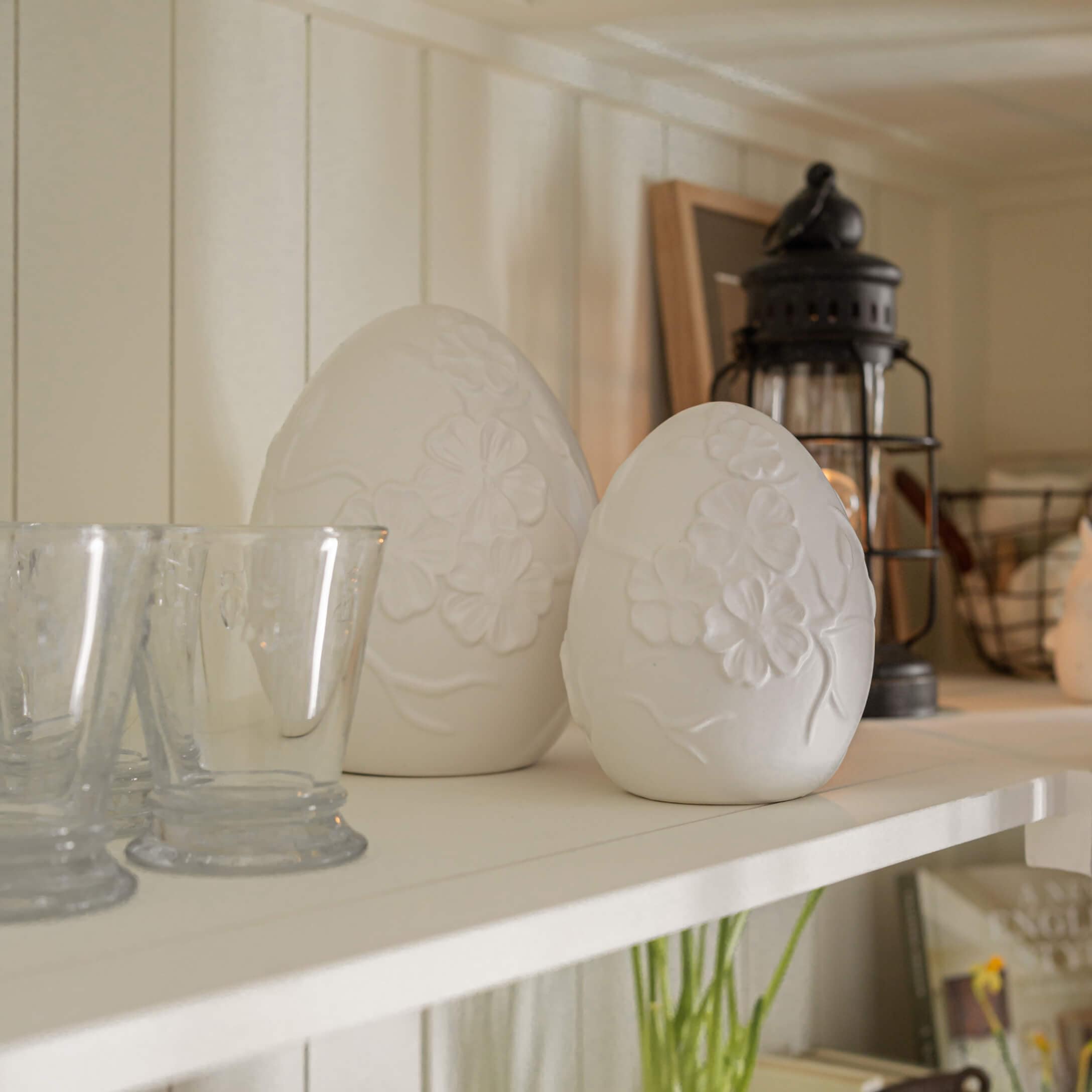Décorations en albâtre blanc en forme d'œufs avec motif floral sur une étagère rustique