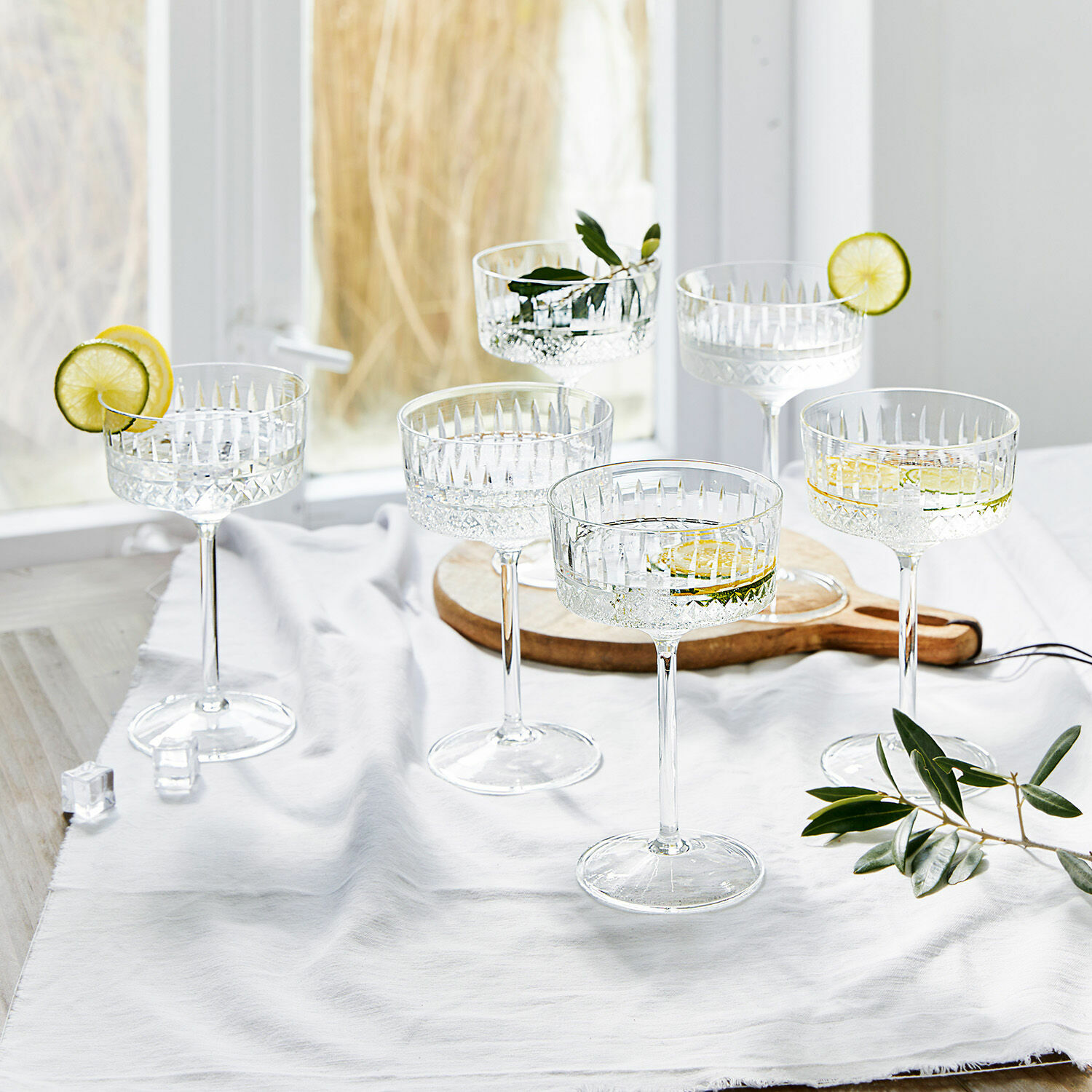 Champagneglas set van 6 Deion Set van zes kristallen cocktailglazen met citroenplakjes en groene bladeren als decoratie