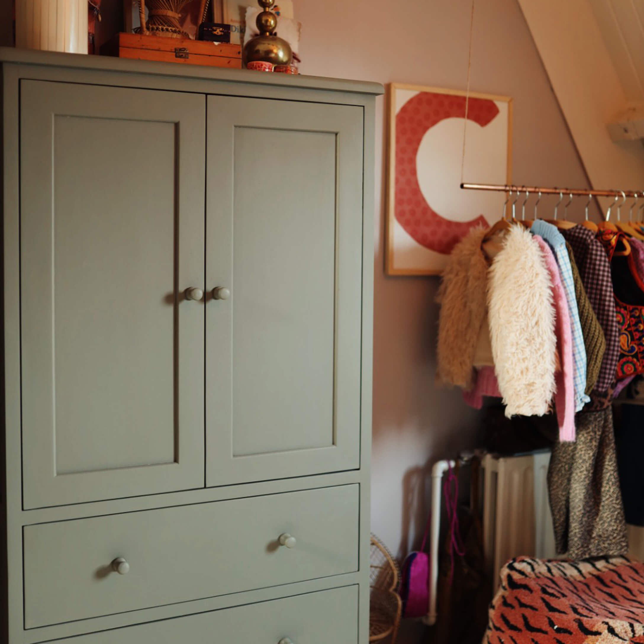Grijze houten kast met twee lades in een gezellige kamer met kleding aan de kapstok